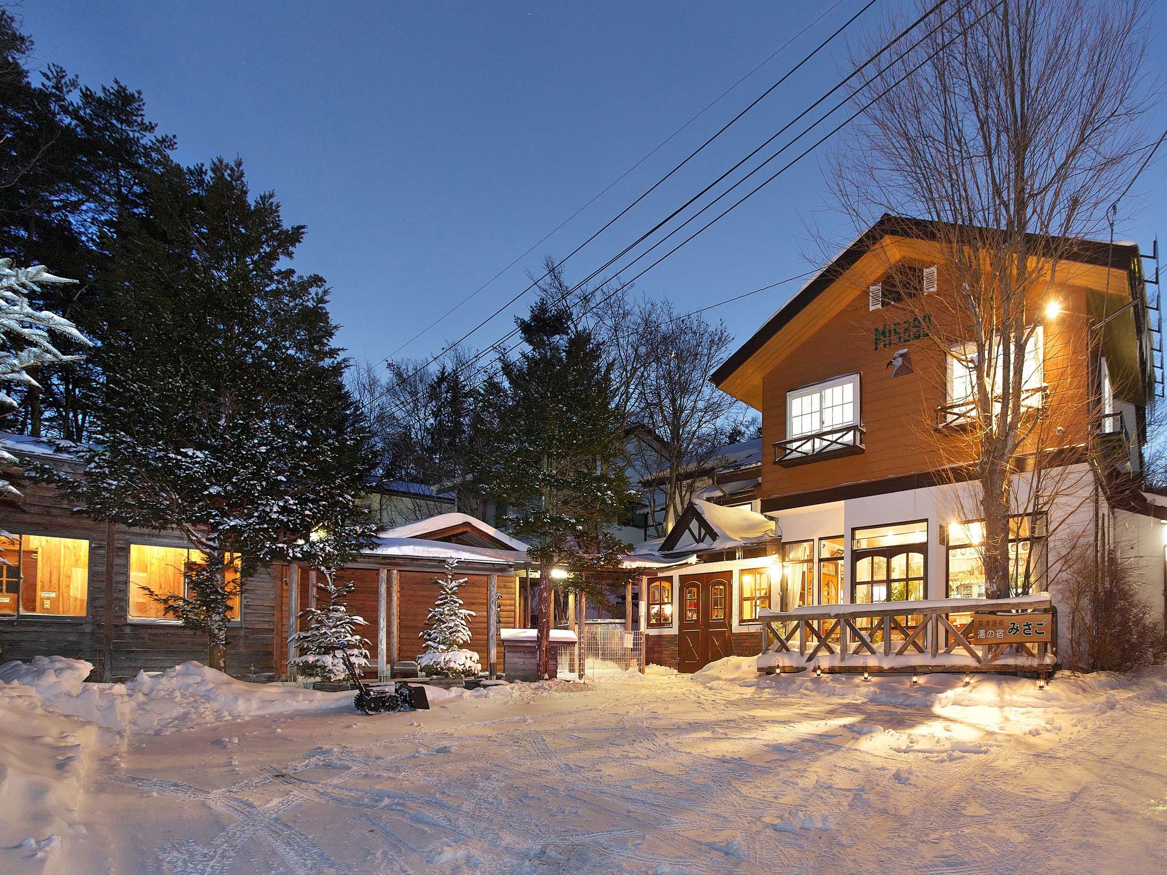 The inn's wooden chalet-style buildings glowing at dusk amid deep snow in winter