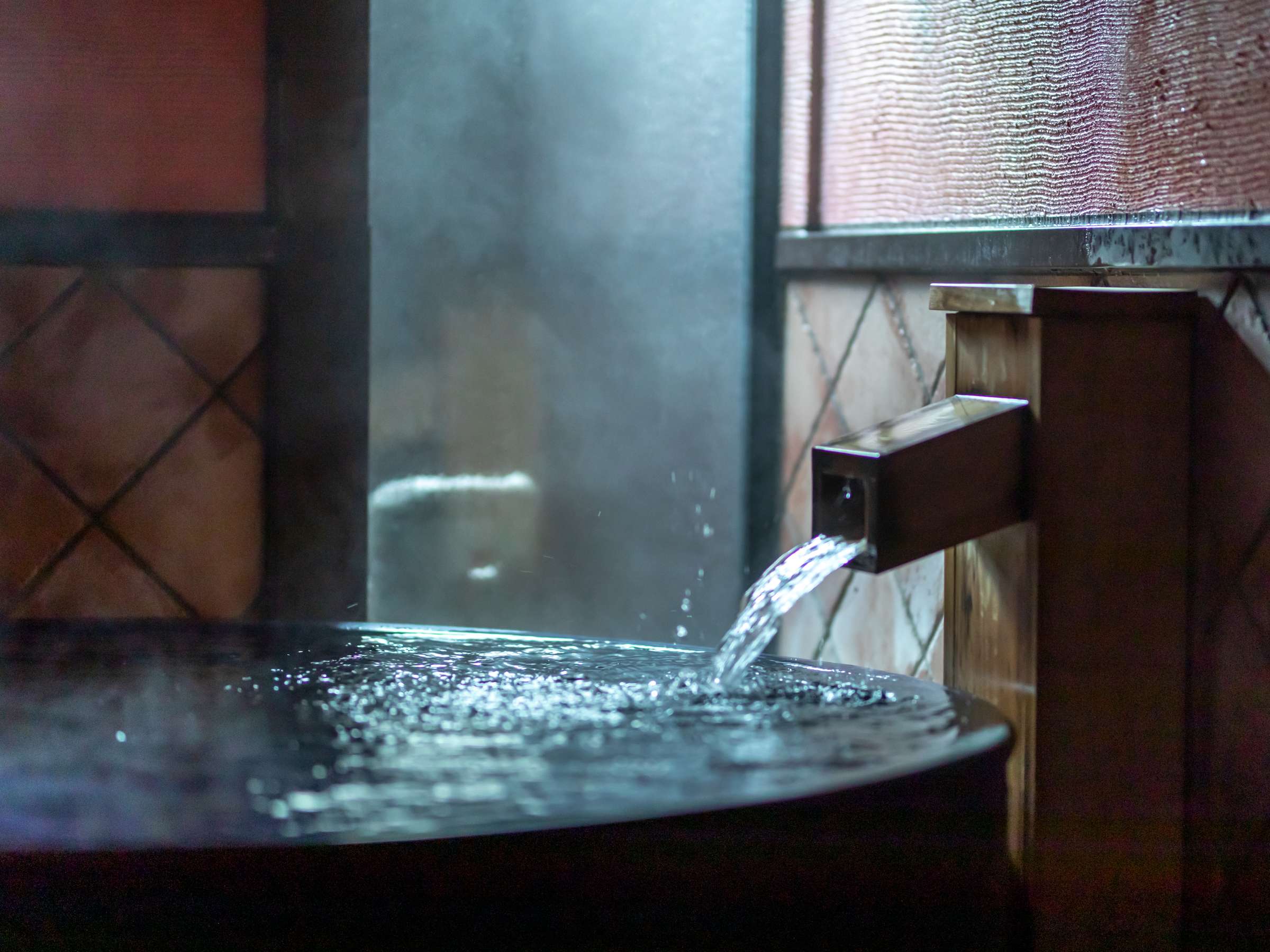 Steaming private bath with hot spring water pouring from a wooden spout into a round tub, Sensui, Kinosaki Onsen