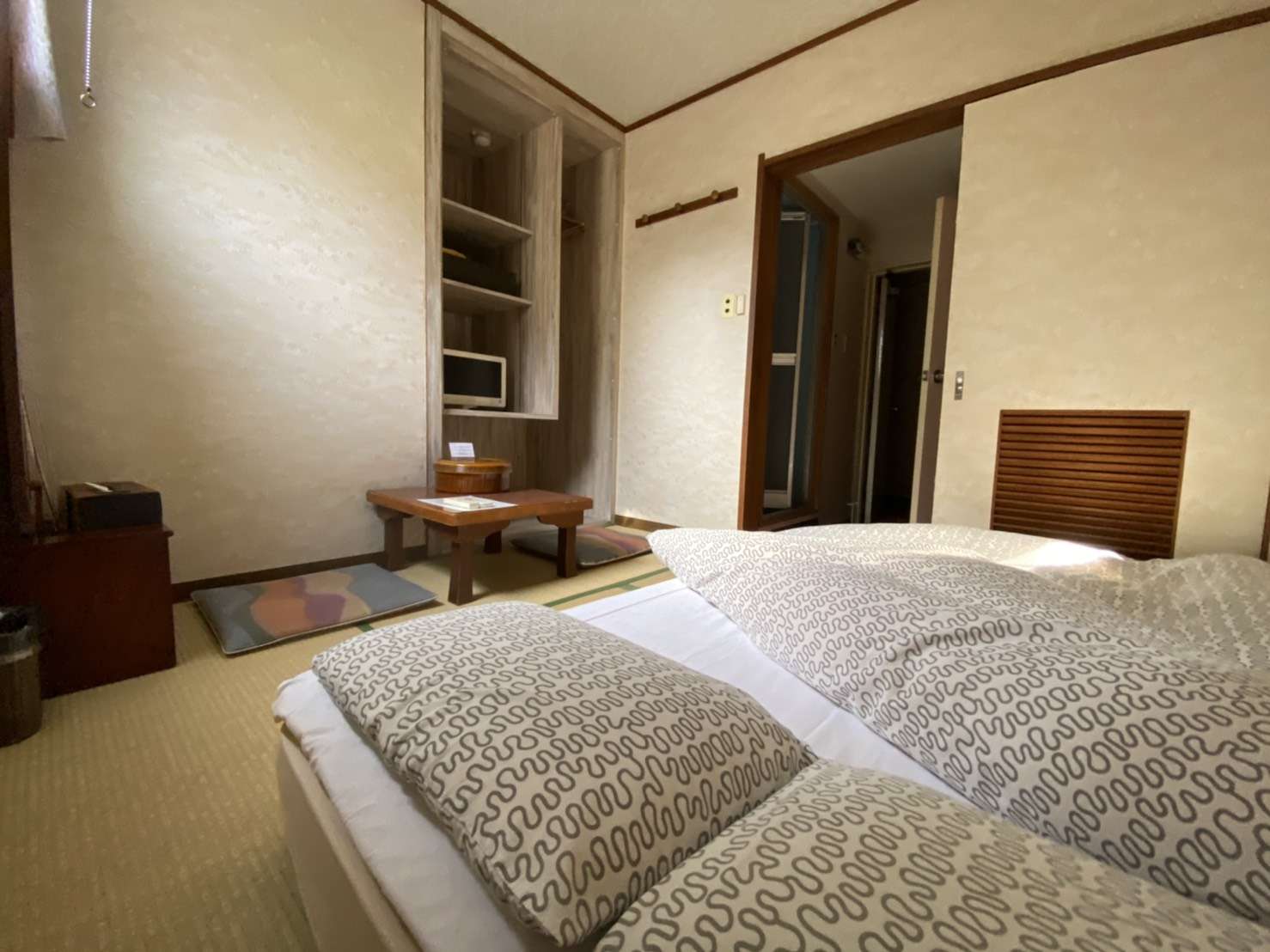 Tatami guest room at Toukaisou with a single futon bed made up, low wooden cabinet and shelved alcove