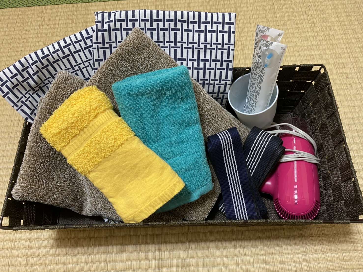 Guest amenity basket with folded towels, yukata cloth and toothbrush set on tatami at Toukaisou