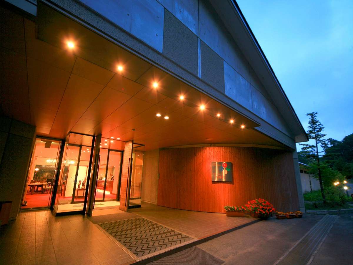 Okunikko Hotel Shikisai illuminated concrete-and-wood entrance at dusk in Nikko