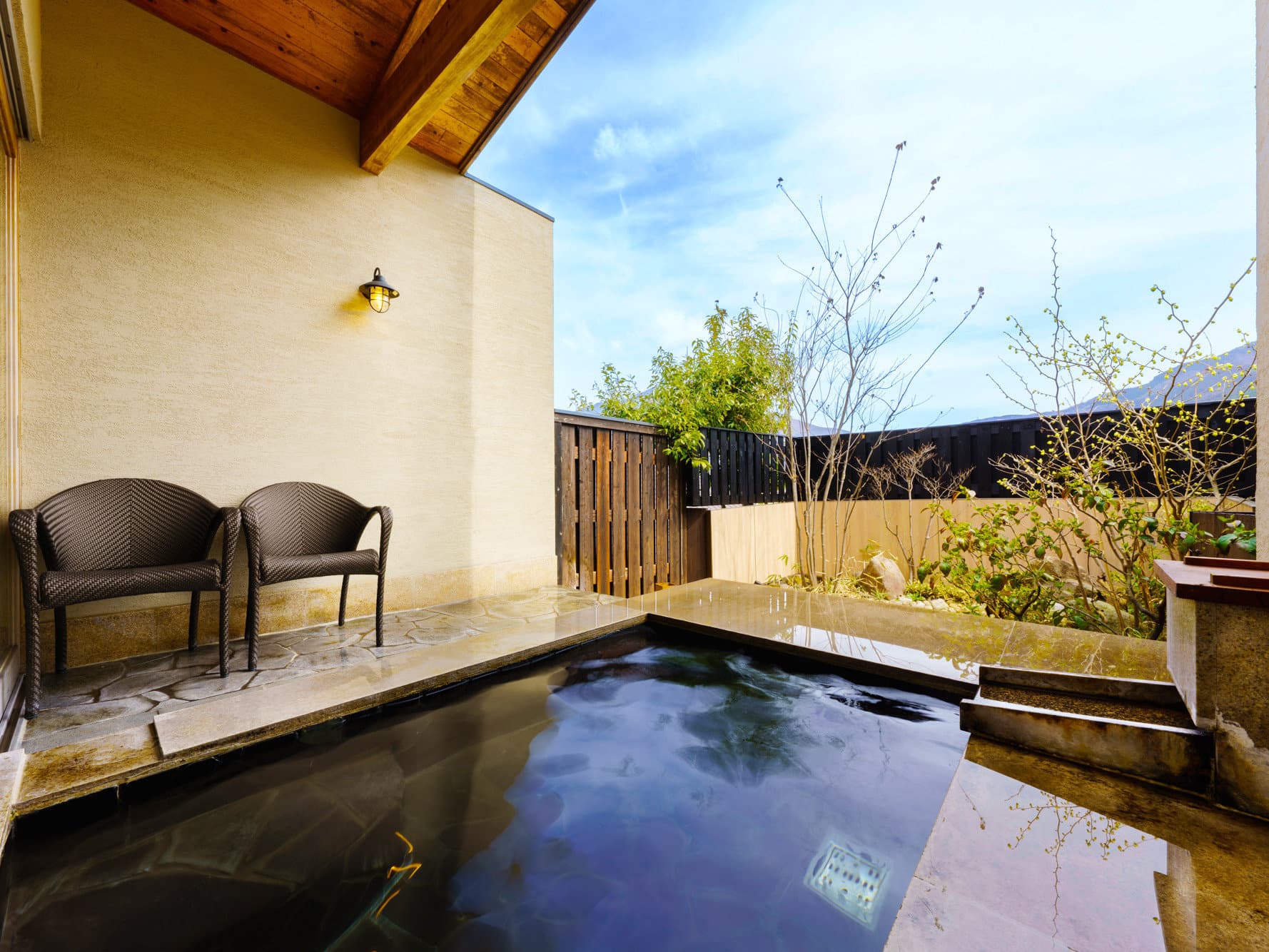 Spacious guest room sitting area at Tosyoan with sofas and a panoramic window overlooking the Yufuin valley