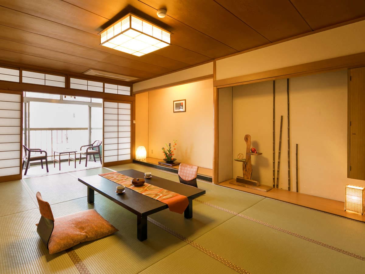 Spacious Japanese tatami guest room with low table, tokonoma alcove and shoji screens at Dogo Grand Hotel