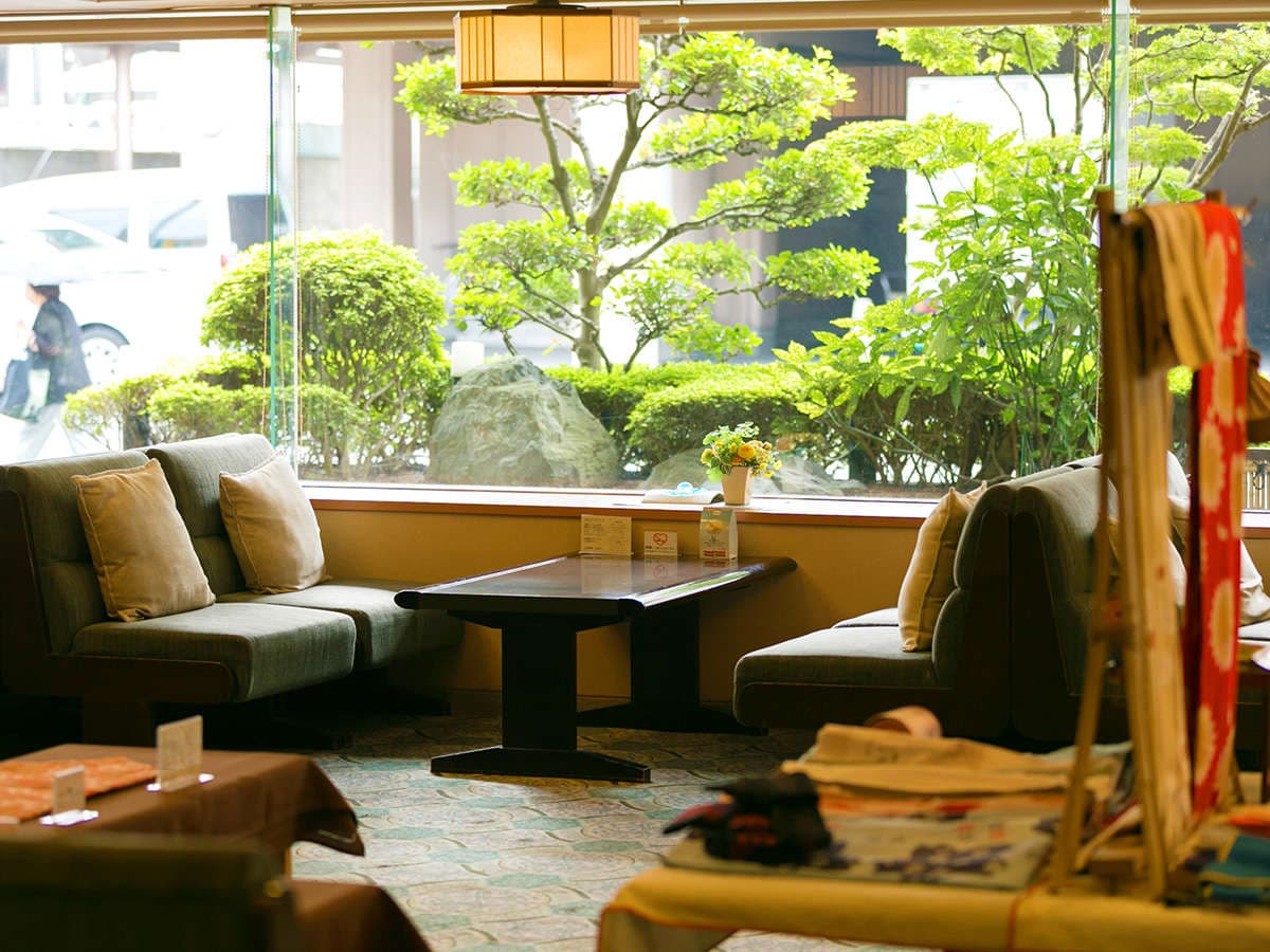 Lobby lounge with sofas overlooking a manicured Japanese garden at Dogo Grand Hotel
