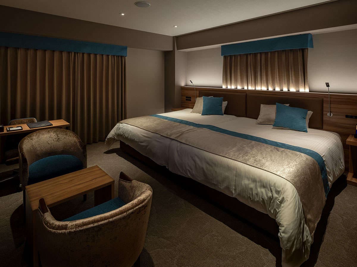 Modern guest room at Wat Hotel & Spa Hida Takayama with a large bed, teal accents and warm evening lighting