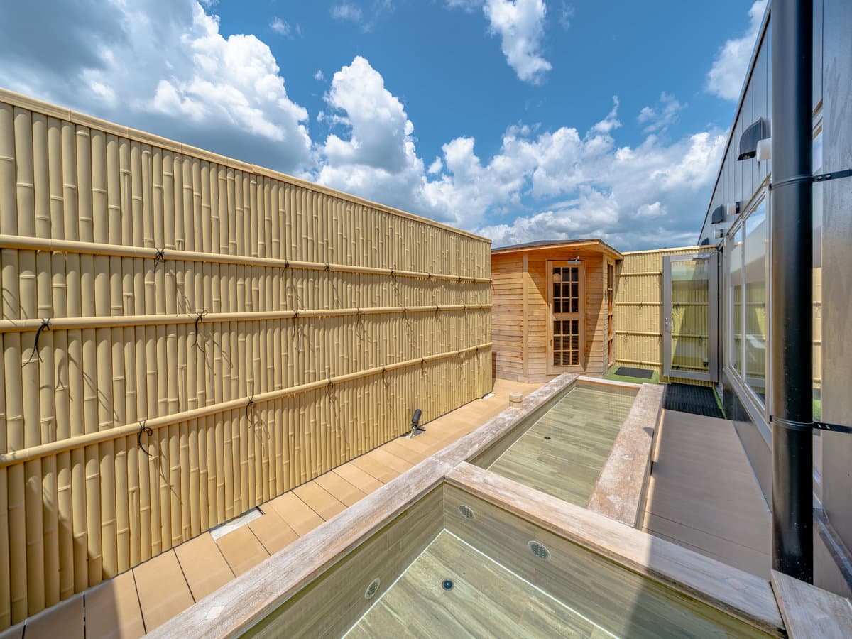 Rooftop open-air bath at Wat Hotel Hida Takayama framed by bamboo screening and a cypress changing house