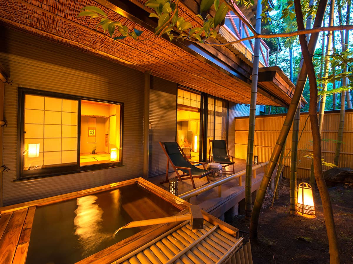 Detached villa exterior with private open-air cypress bath and bamboo grove illuminated at dusk at Kinugawa Park Hotels