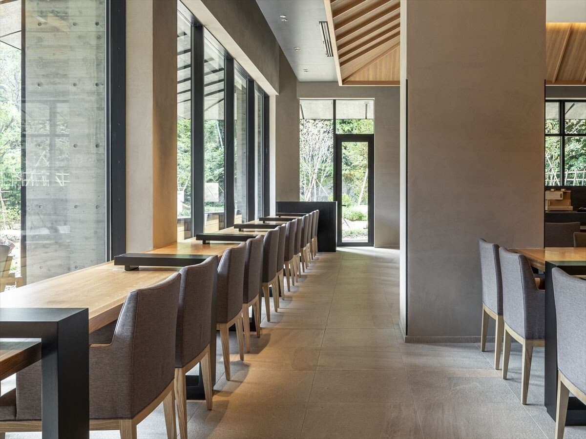 Counter dining seats along floor-to-ceiling windows facing the forest at SOKI ATAMI