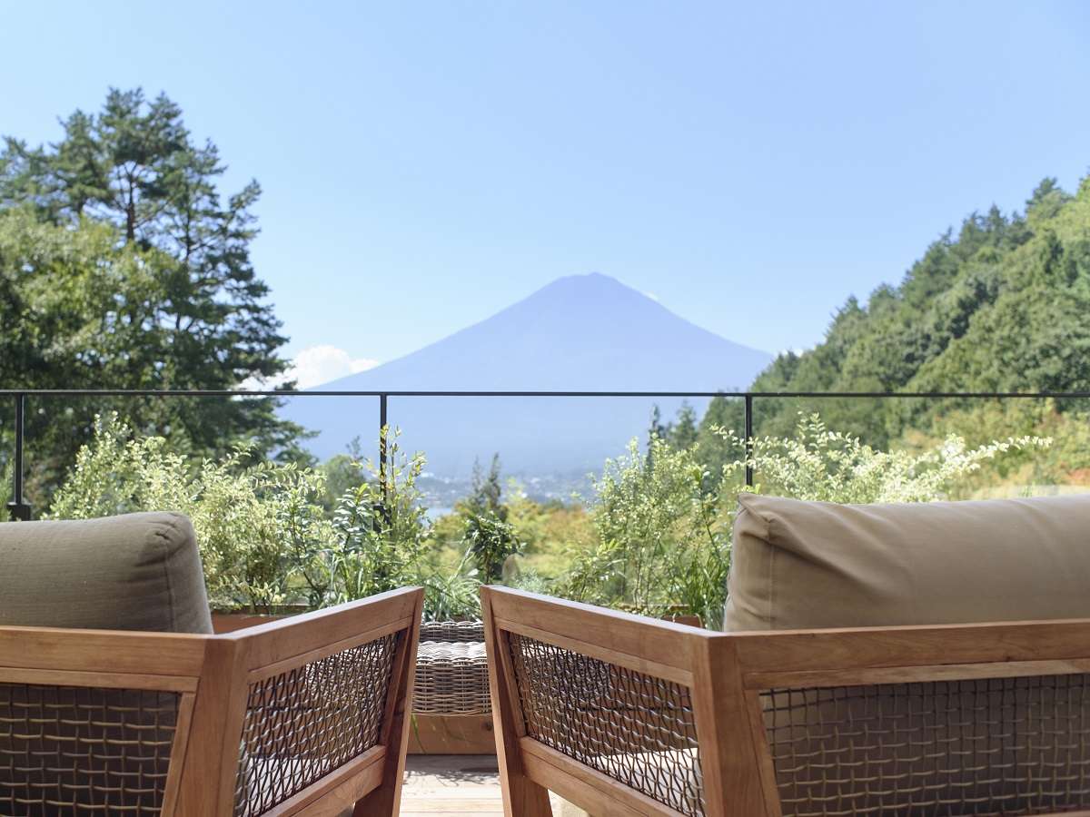 Mt Fuji viewed over a planted terrace railing from teak lounge chairs at Fufu Kawaguchiko