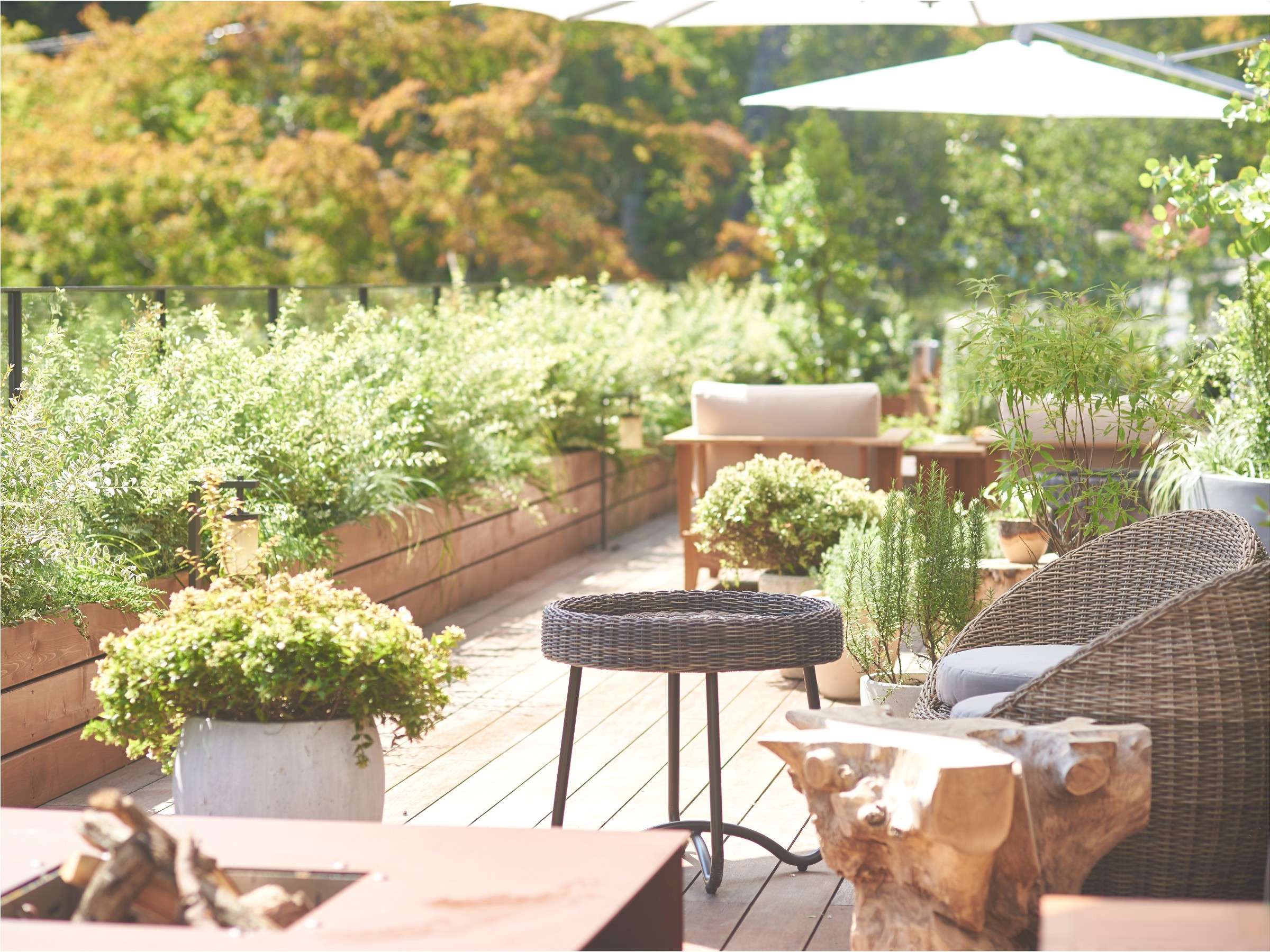 Sunlit rooftop garden terrace with raised herb planters and woven lounge seating at Fufu Kawaguchiko