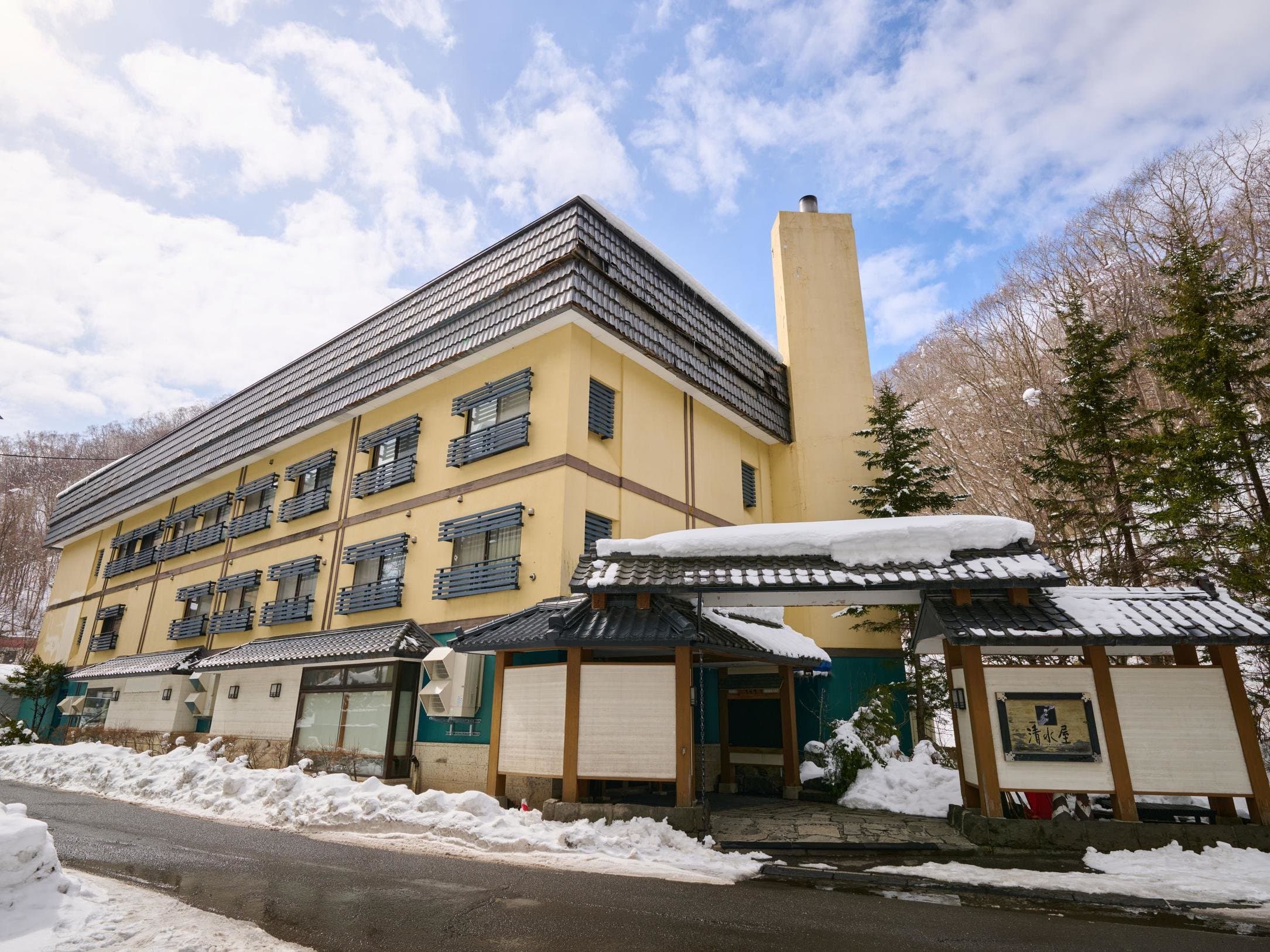 Snow-covered exterior of Oyado Kiyomizuya ryokan with traditional tiled-roof entrance gate in Noboribetsu Onsen, Hokkaido
