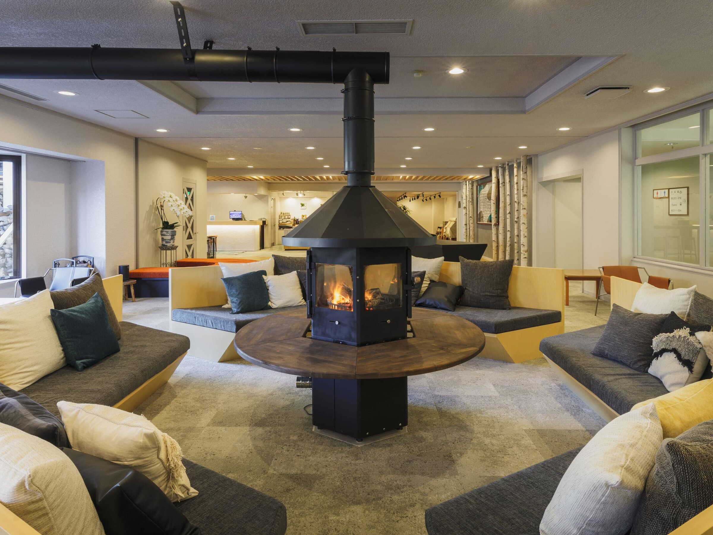 Lounge at Hotel Jurin in Zao Onsen with a central wood-burning fireplace ringed by sofas