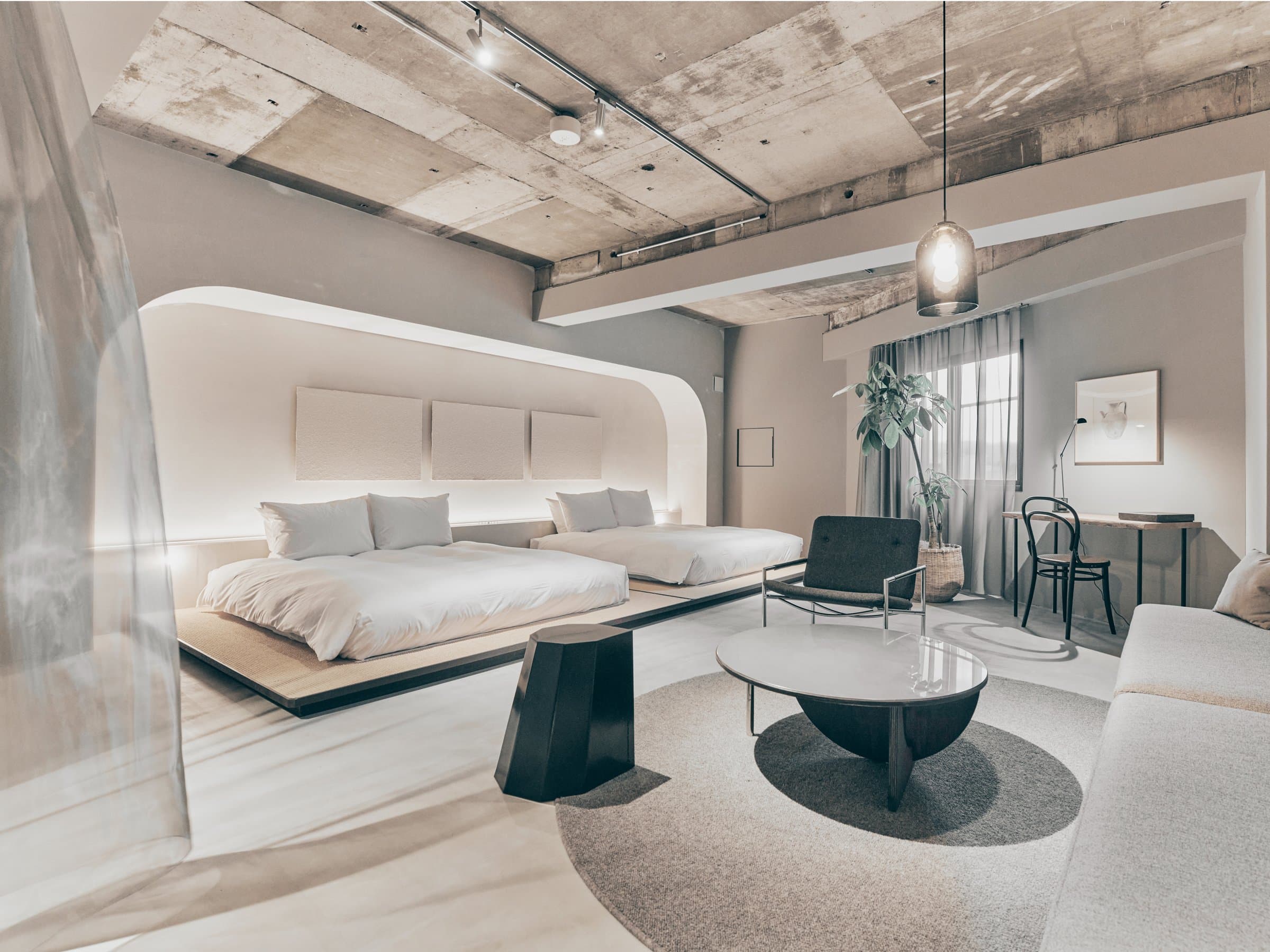 Korinkyo boutique hotel guest room in Kanazawa with curved plaster headboard, twin beds and minimalist concrete-ceiling design