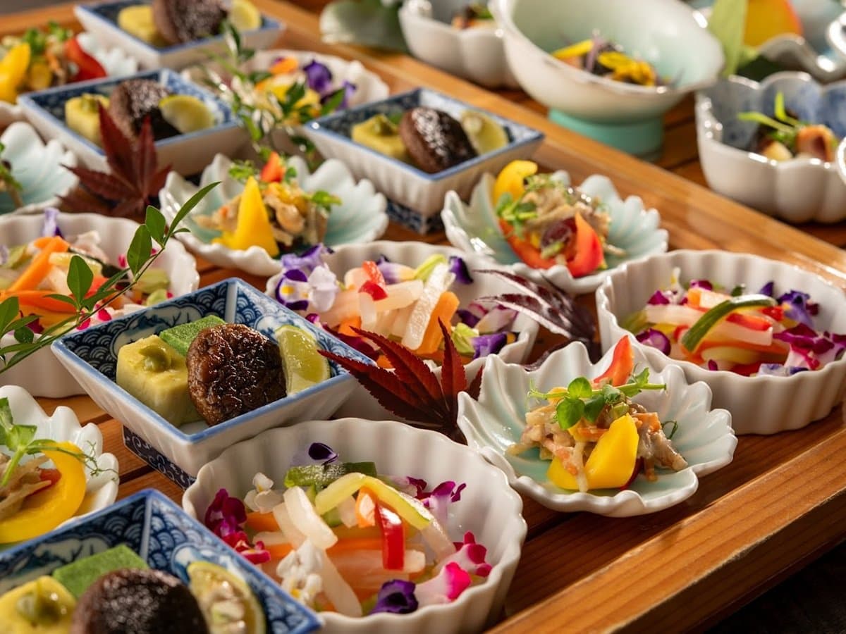 Colourful kaiseki appetizer course of small seasonal dishes arranged on a wooden tray