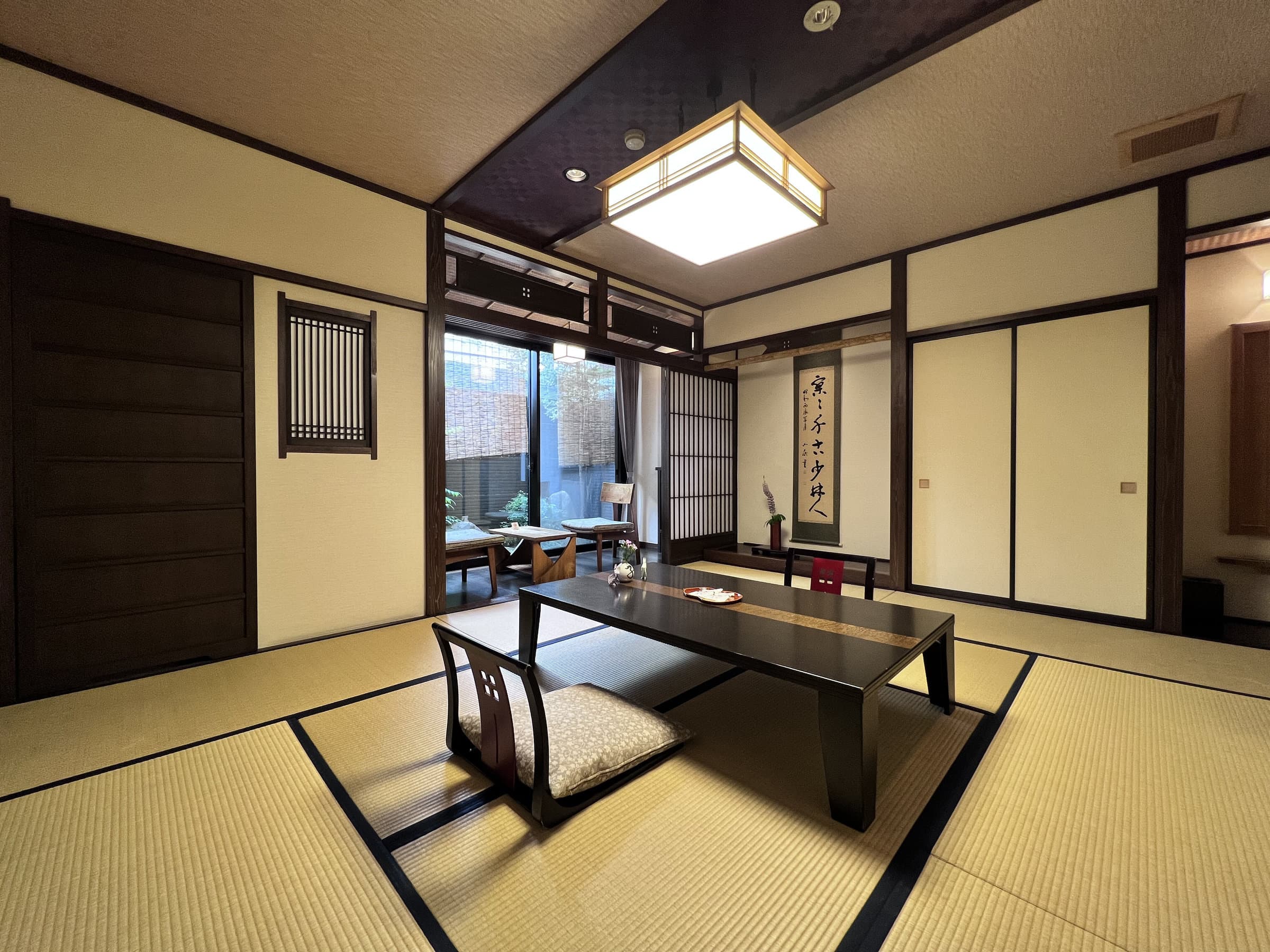 Spacious tatami guest room with low table and hanging calligraphy scroll at Ryokan Tanabe in Takayama