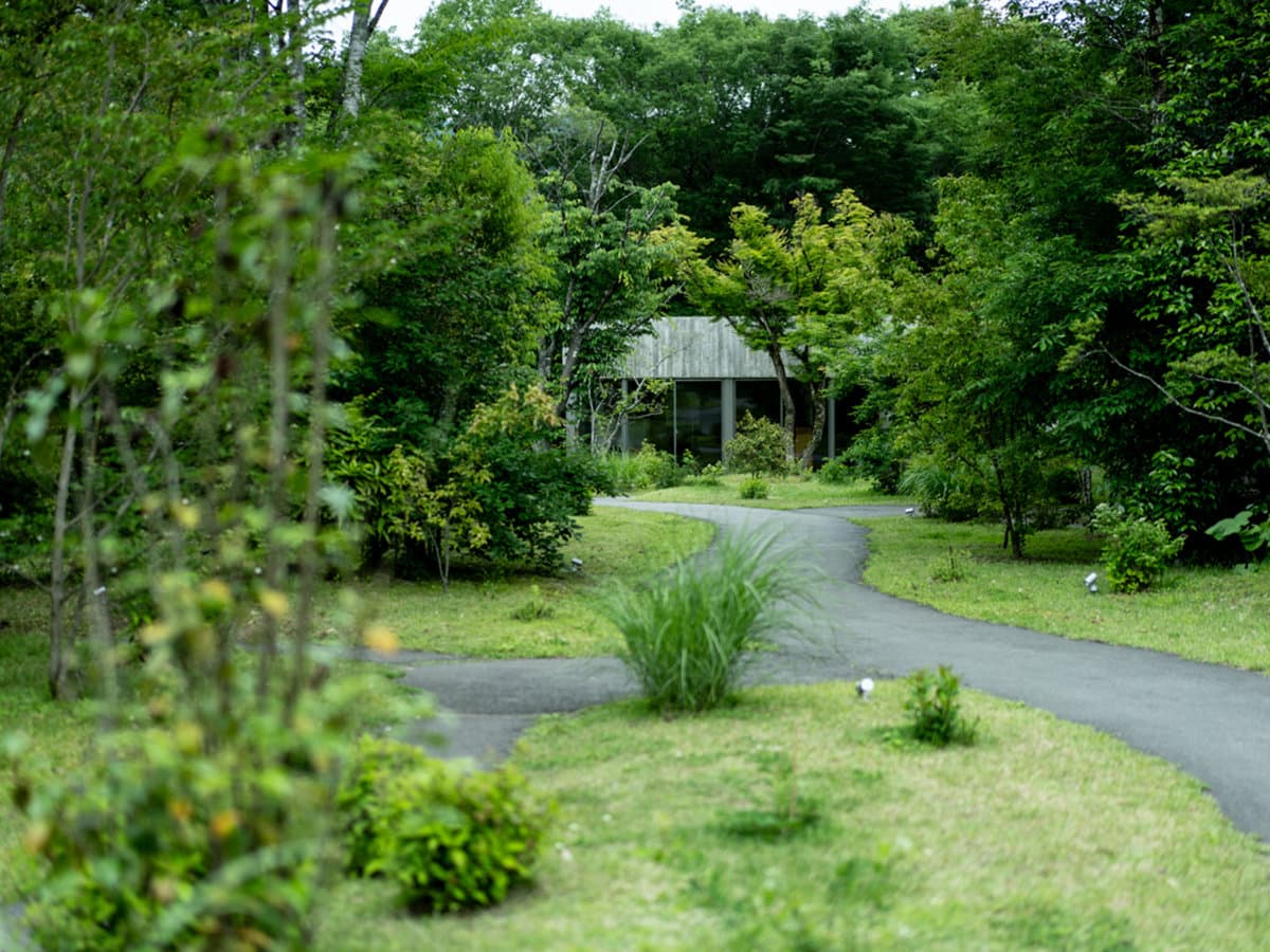 Lush private garden with a winding path leading to a guest villa at Sanso Warabino in Yufuin