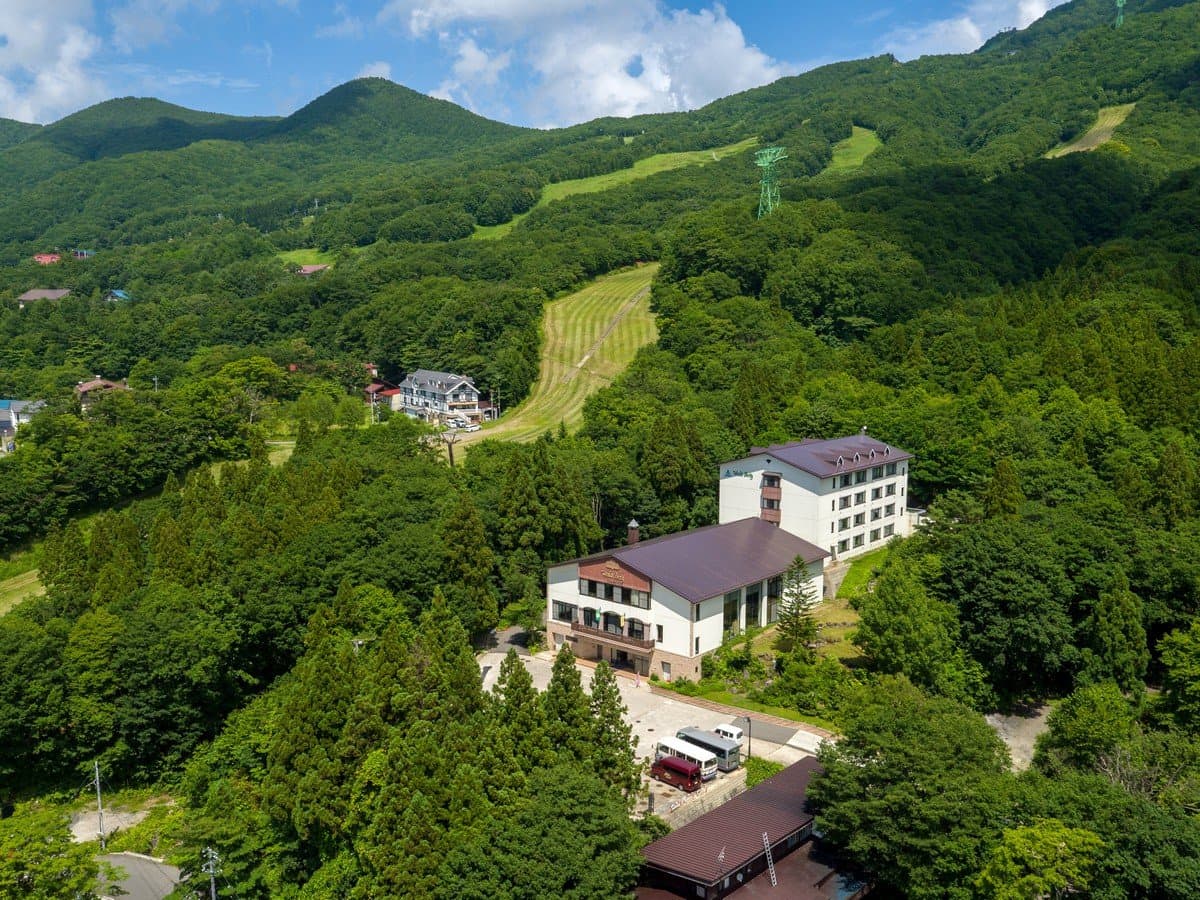 Aerial view of Hotel Waldberg surrounded by green mountains and ski slopes at Zao Onsen