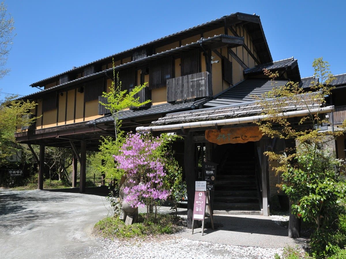 Iyashi-no-Sato Kiyashiki ryokan exterior, full wooden building under a blue sky in Kurokawa Onsen