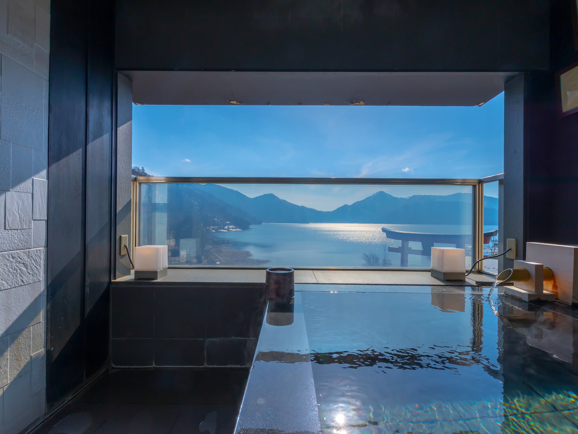 Indoor bath at Hotel Hana-An with a picture window framing Lake Chuzenji and the lakeside torii gate