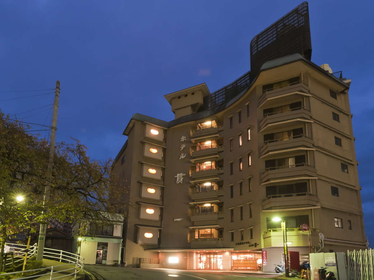 Hotel Kanichi multi-story exterior illuminated at dusk near Atami Onsen seafront