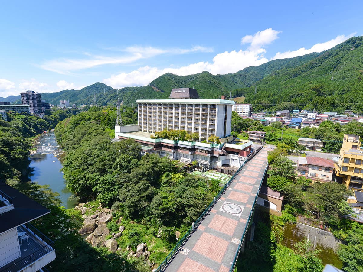Aerial daytime view of the hotel beside the emerald Kinugawa River and forested mountains of Nikko