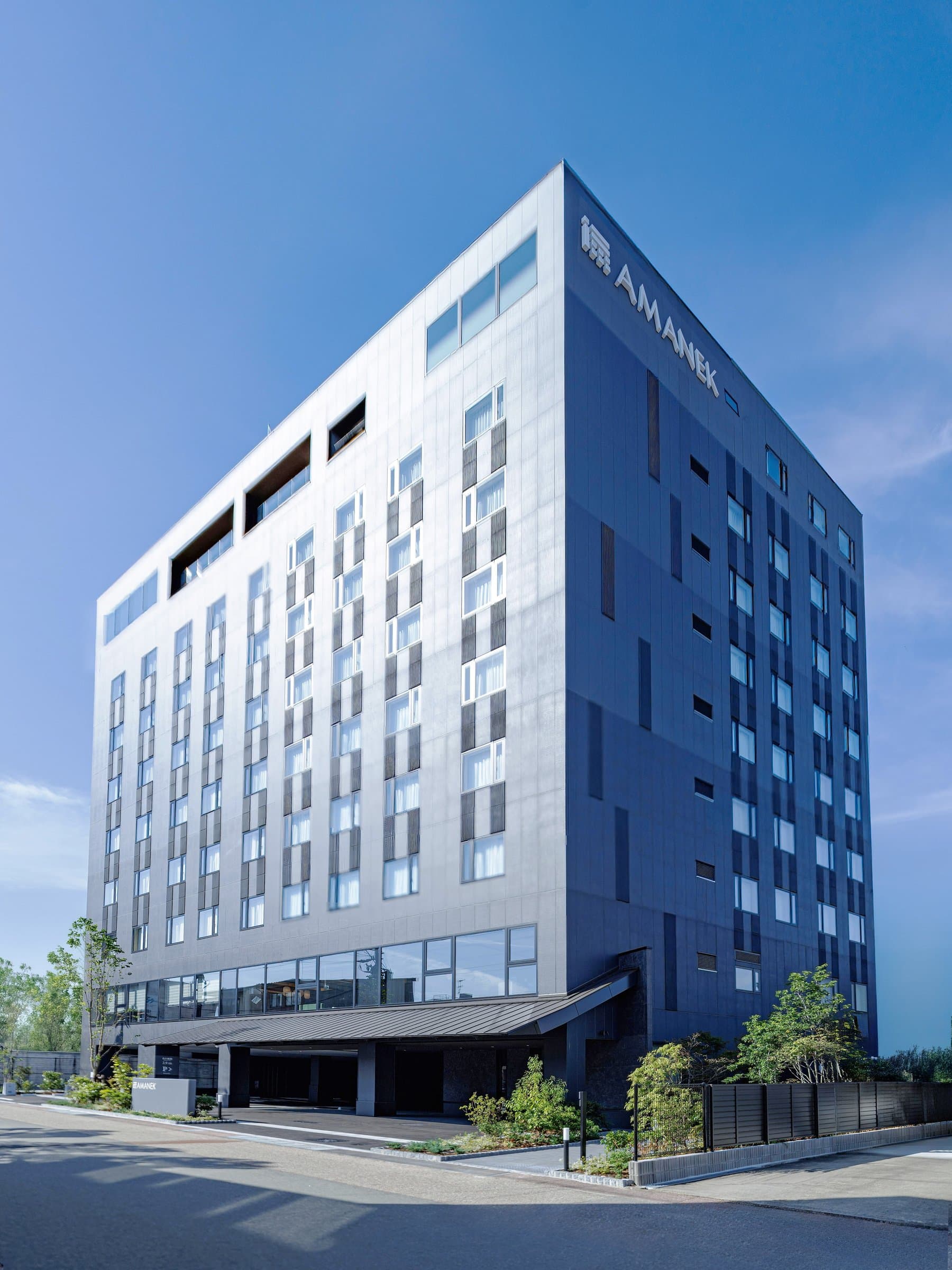 Exterior of HOTEL AMANEK Hida Takayama, a modern multi-storey hotel under blue sky in Takayama