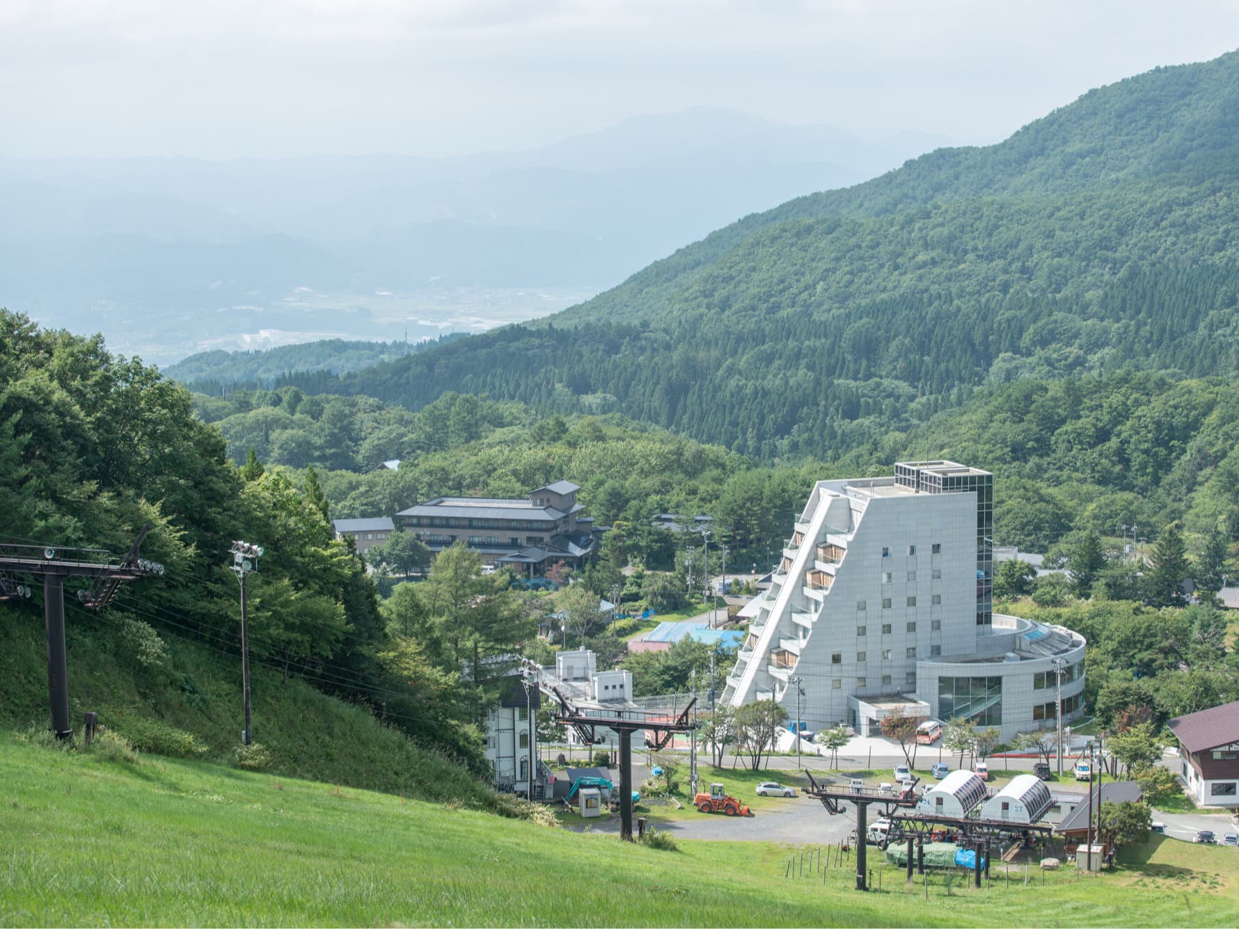 Exterior of Takamiya Rurikura Resort rising on a green mountain slope above Zao Onsen
