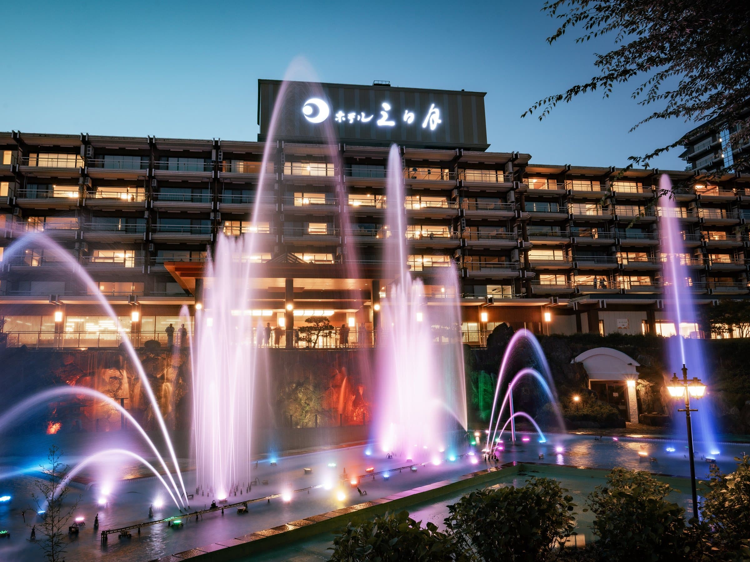 Nikko Kinugawa Hotel Mikazuki illuminated at night with a colorful fountain show in the courtyard