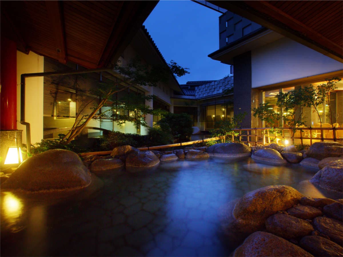 Outdoor rock rotenburo bath lit at dusk in a garden courtyard at Hotel New Mitoya, Akiu Onsen near Sendai