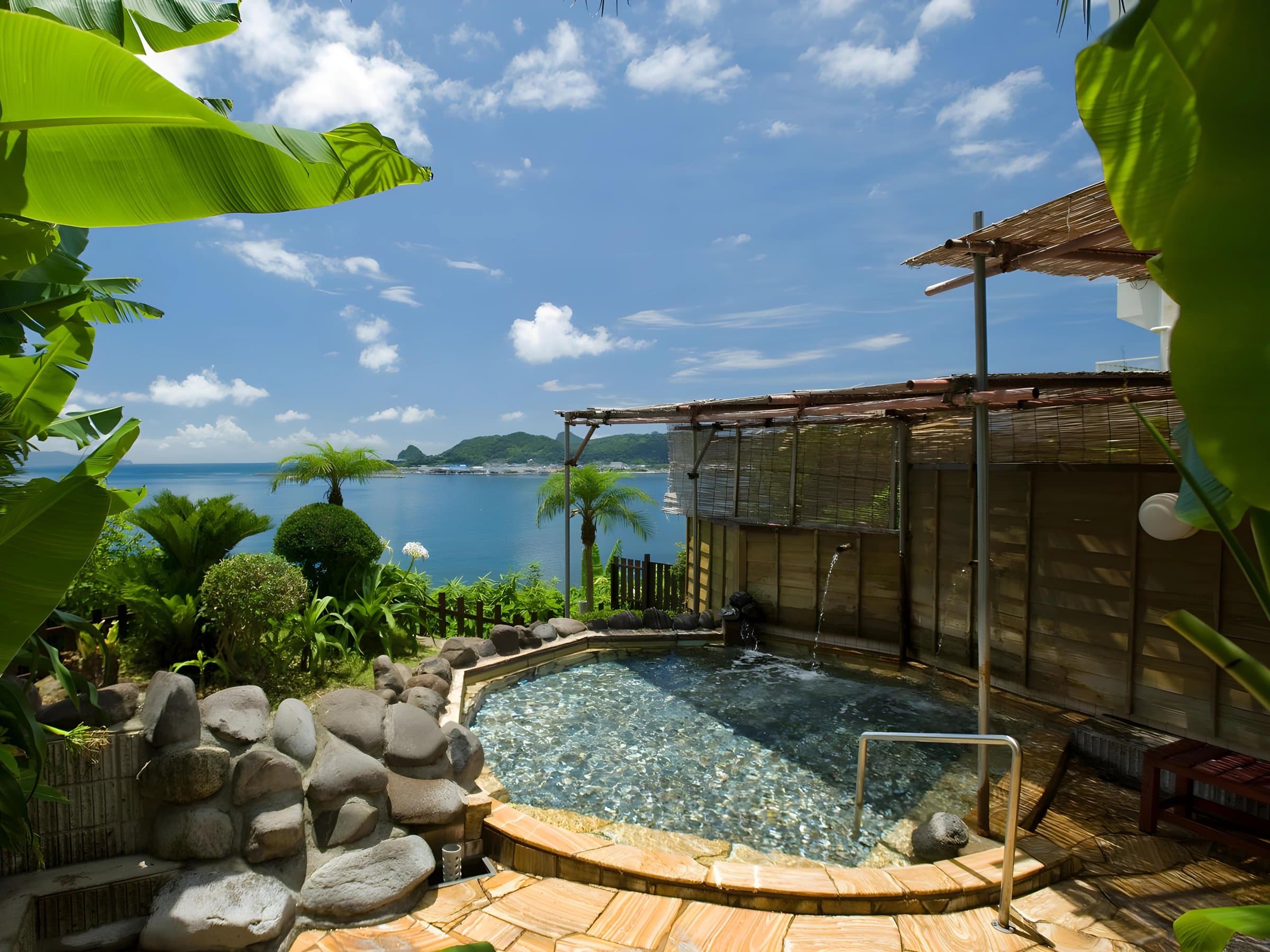 Seaside open-air rotenburo framed by tropical foliage overlooking Kinko Bay at Ibusuki Royal Hotel, Ibusuki Onsen