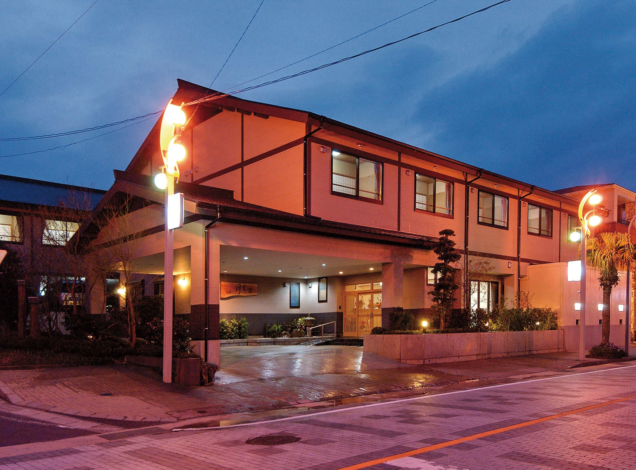 Ryokan Tsukimiso front entrance and porte-cochere illuminated at dusk in Ibusuki Onsen