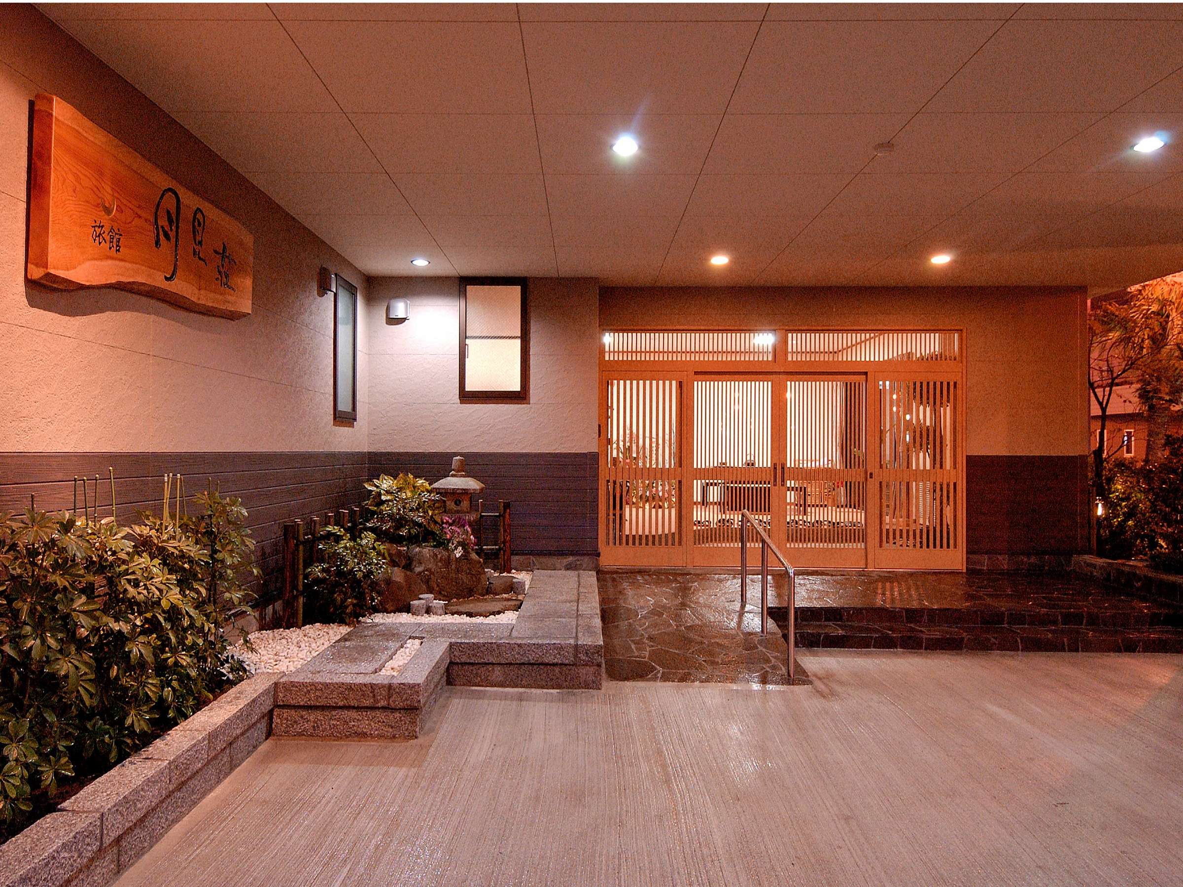 Ryokan Tsukimiso entrance and wooden signboard lit at dusk near the Ibusuki sand-steam beach