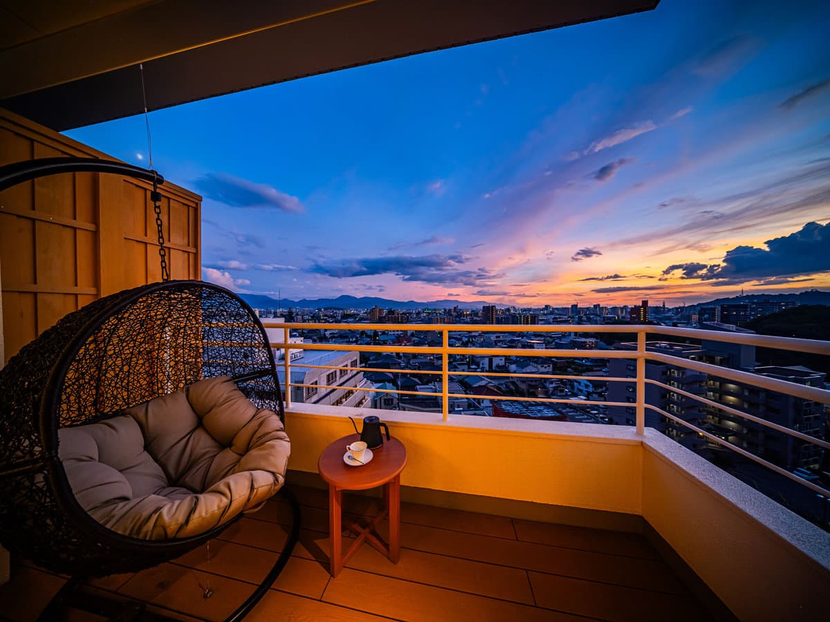 Private terrace at Dogo Prince Hotel with a hanging chair overlooking Matsuyama rooftops at sunset, Dogo Onsen