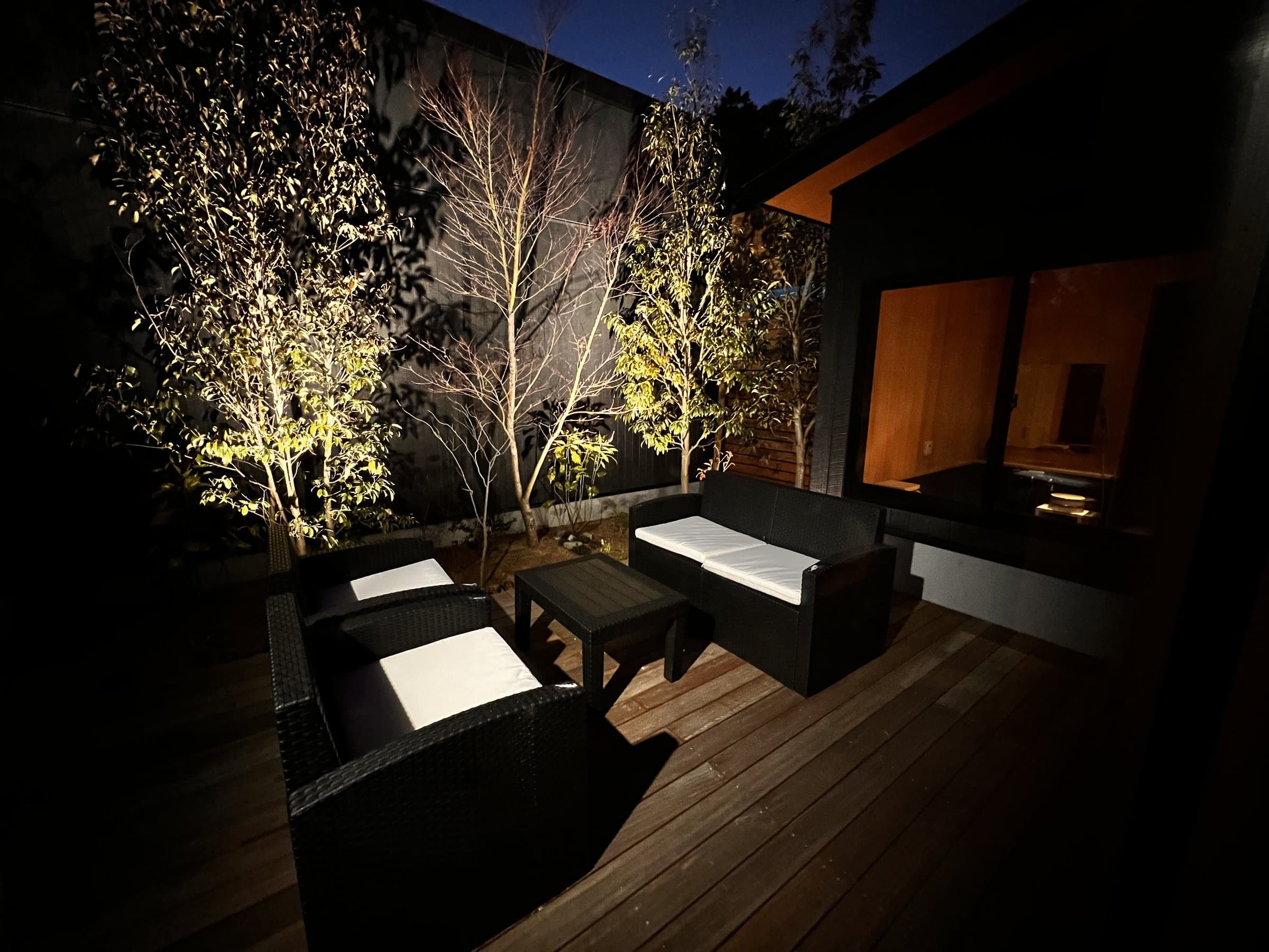 Private wooden terrace with illuminated trees and lounge seating at dusk at Yamanote Bettei Hagakure