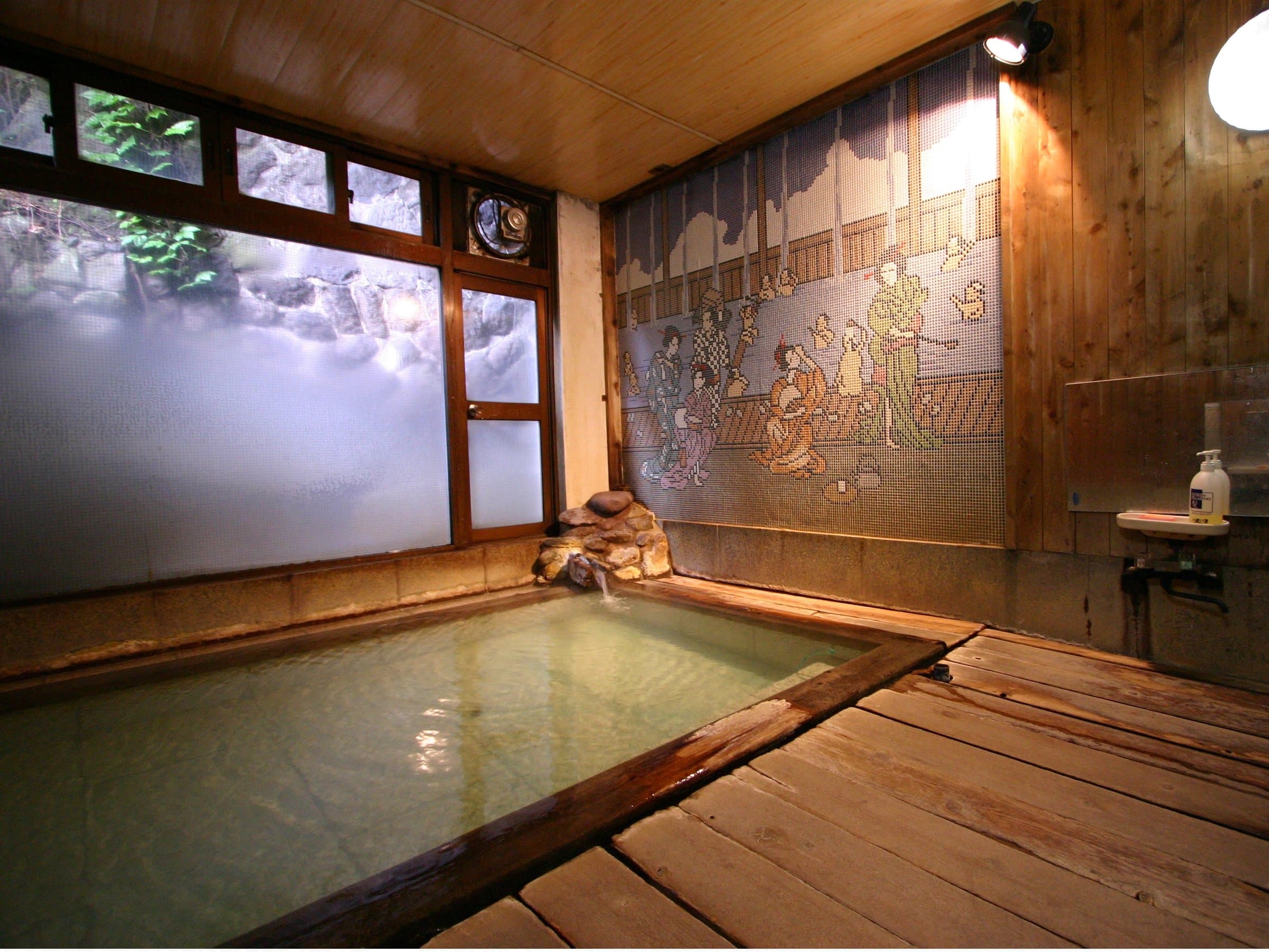 Steaming indoor hot spring bath with wooden deck and a classic painted tile mural on the wall