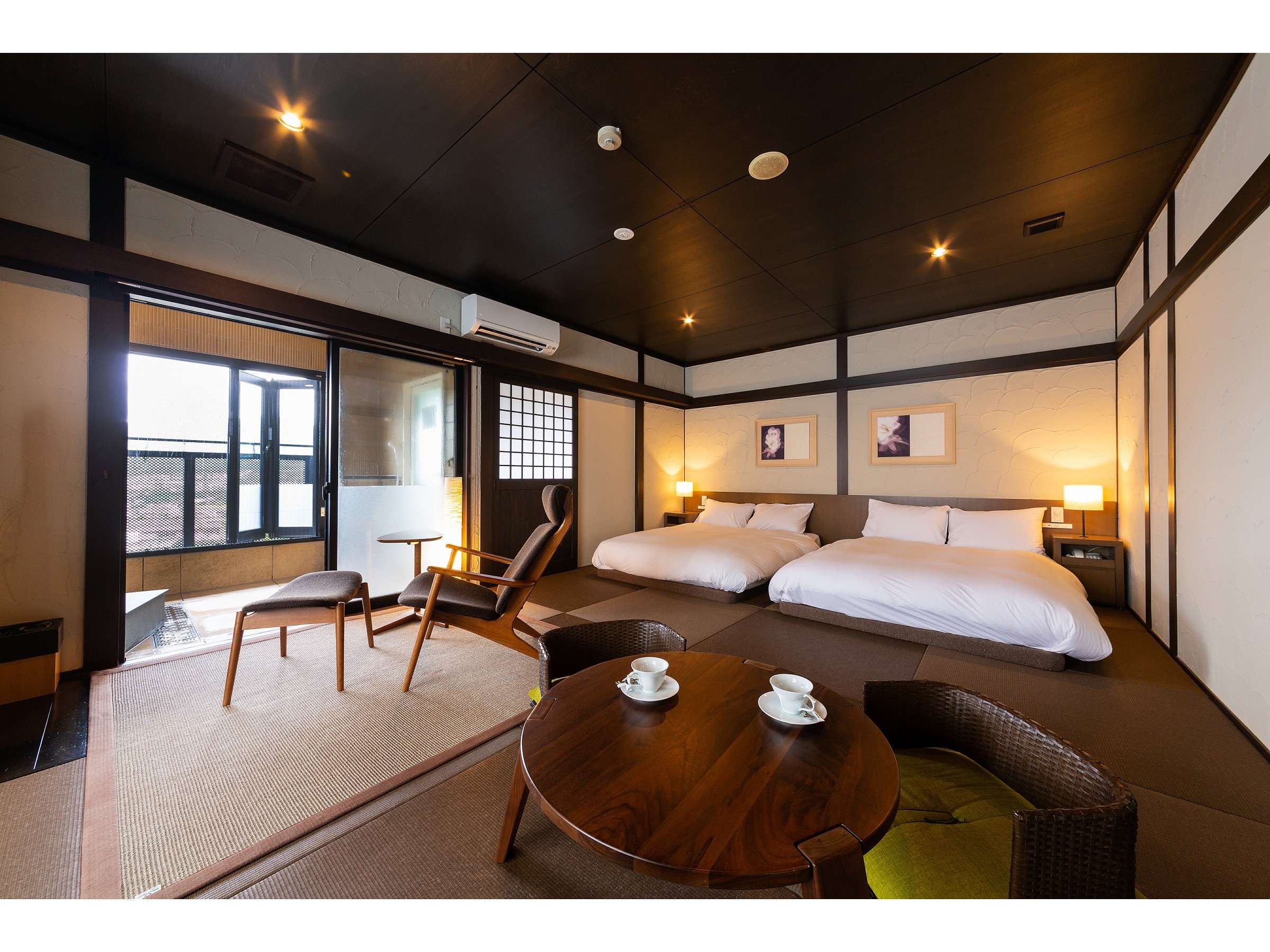 Modern tatami guest room at Bisei Yufuin with twin low beds, lounge chairs and a private bath alcove