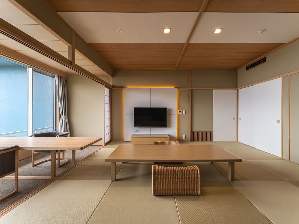 Spacious traditional tatami guest room with low wooden table and shoji screens at ISHINOYA Atami