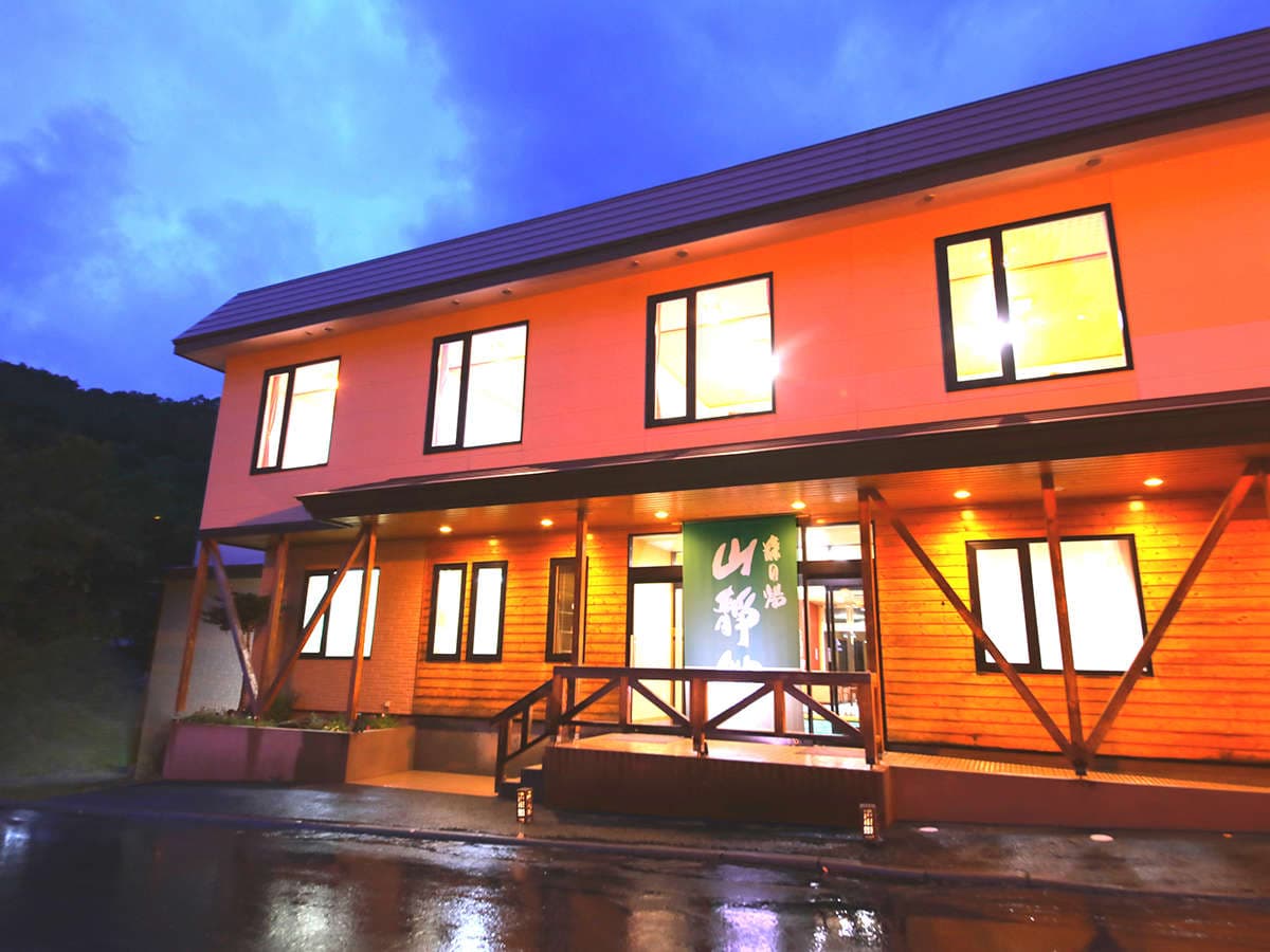Mori no Yu Sanseikan ryokan exterior illuminated at dusk with wood-clad entrance in Karurusu Onsen, Noboribetsu