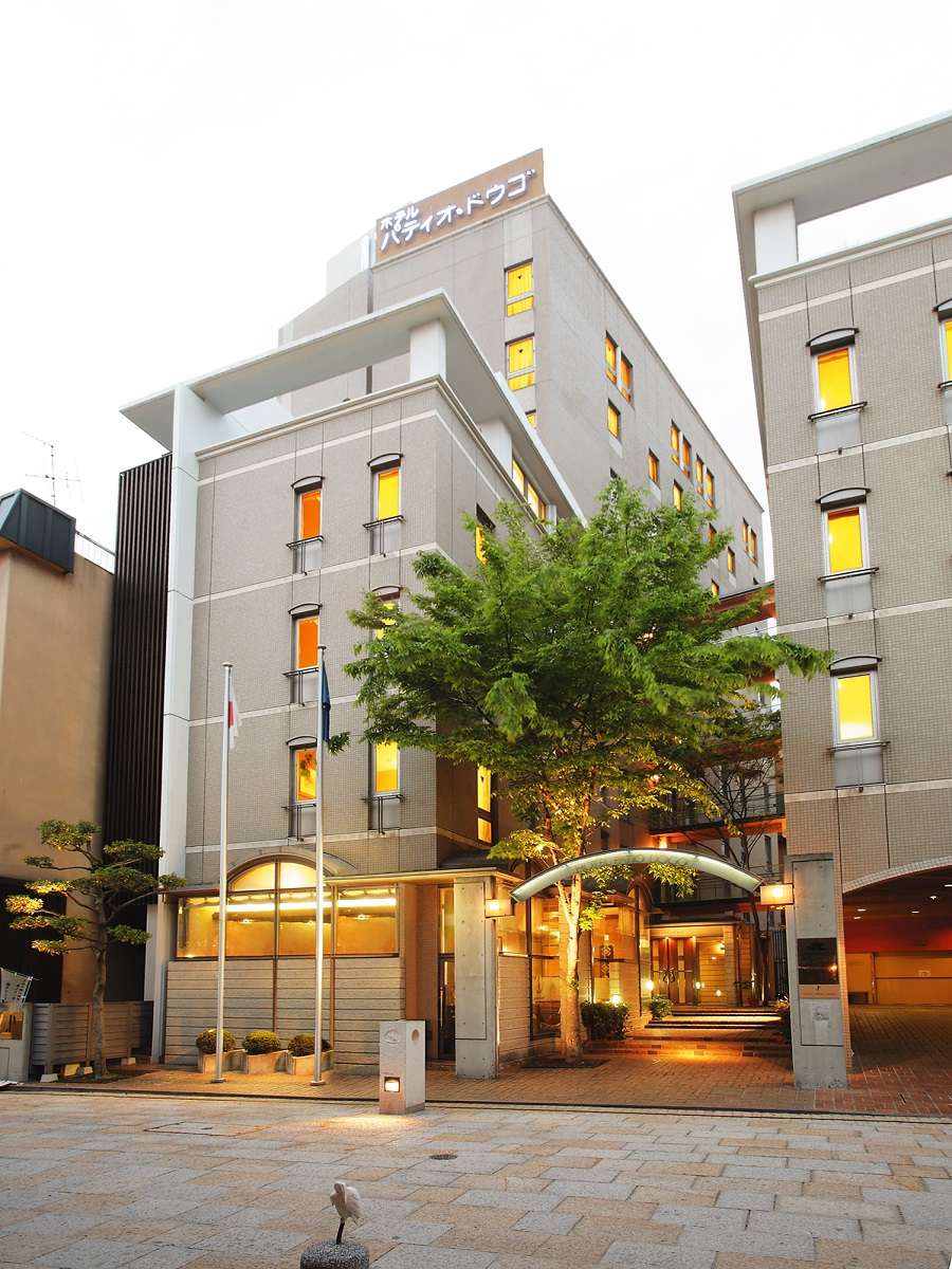 Hotel Patio Dogo full building exterior at dusk with illuminated entrance arch near Dogo Onsen, Matsuyama