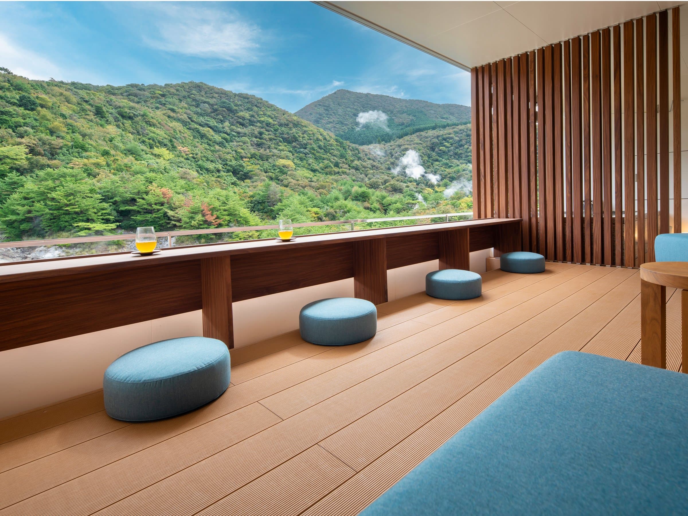 Window terrace seating at KAI Unzen with low cushions overlooking the green Unzen mountains and rising hot-spring steam
