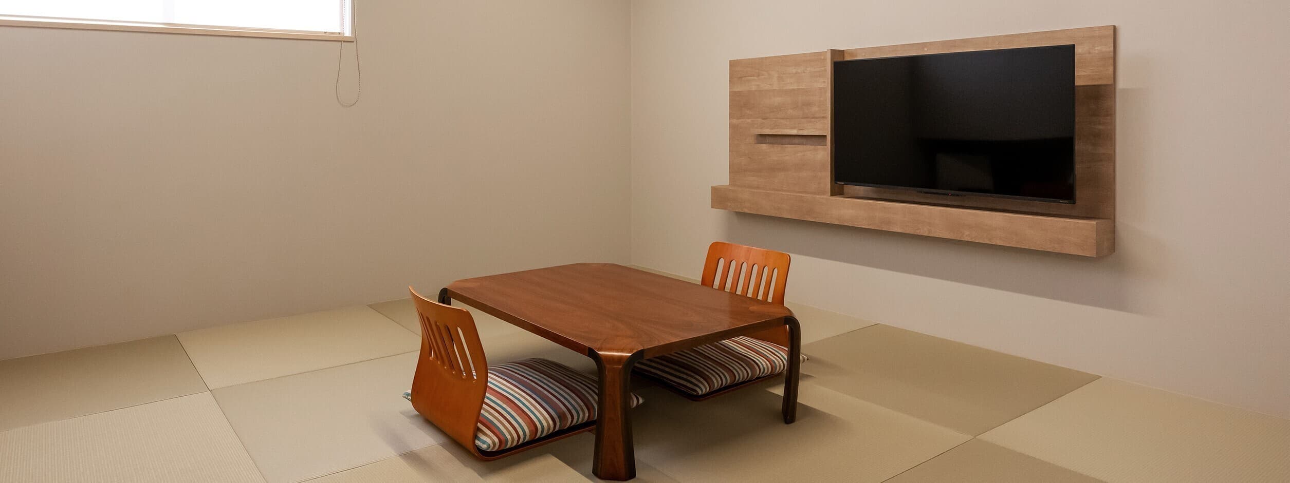 Renovated Japanese-style guest room at Kusatsu Onsen Hoshikawa with borderless tatami, a low wooden table and floor chairs
