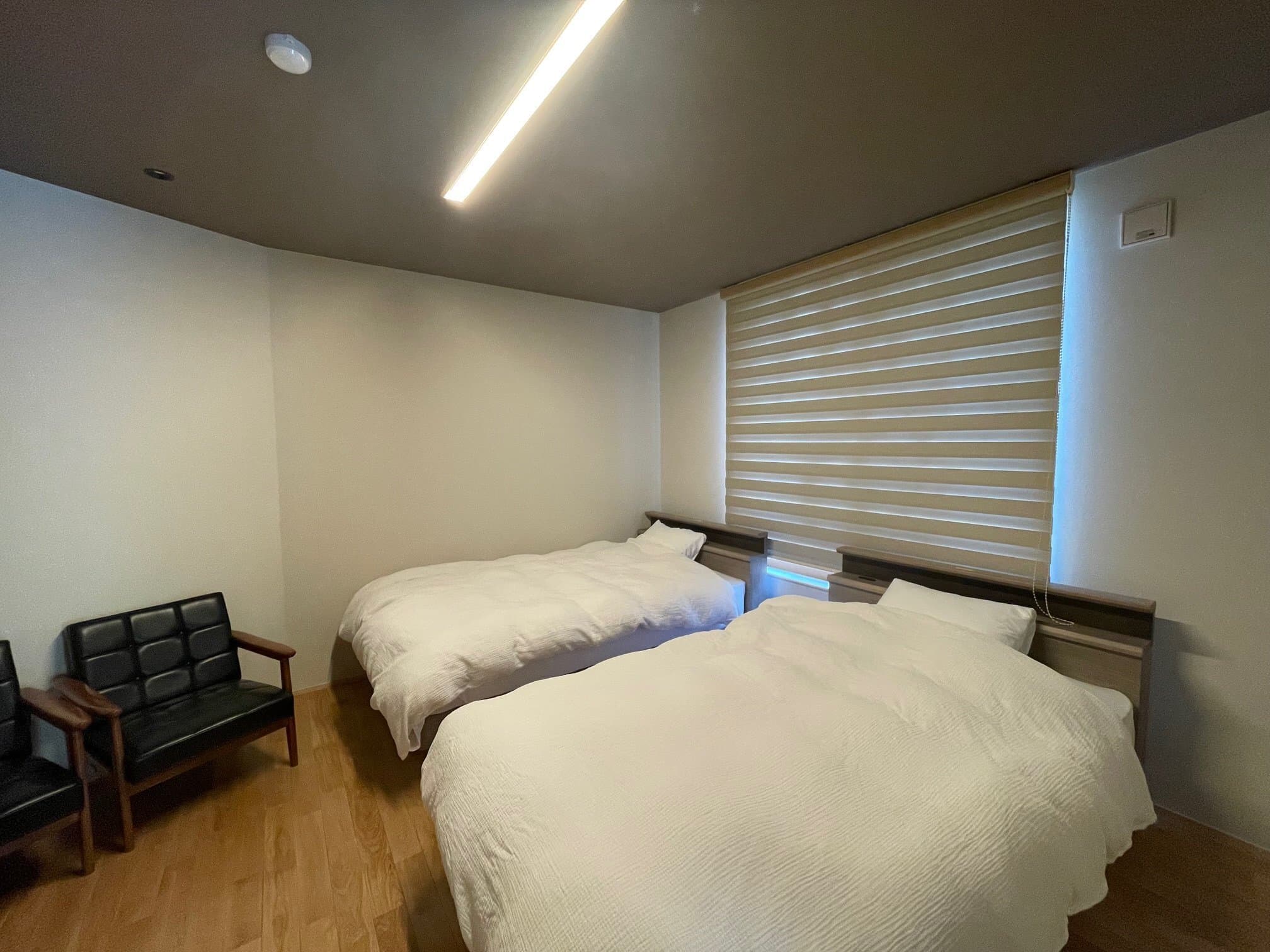 Twin-bed guest room at Kusatsu Onsen Hoshikawa with low beds, wooden flooring and a lounge chair