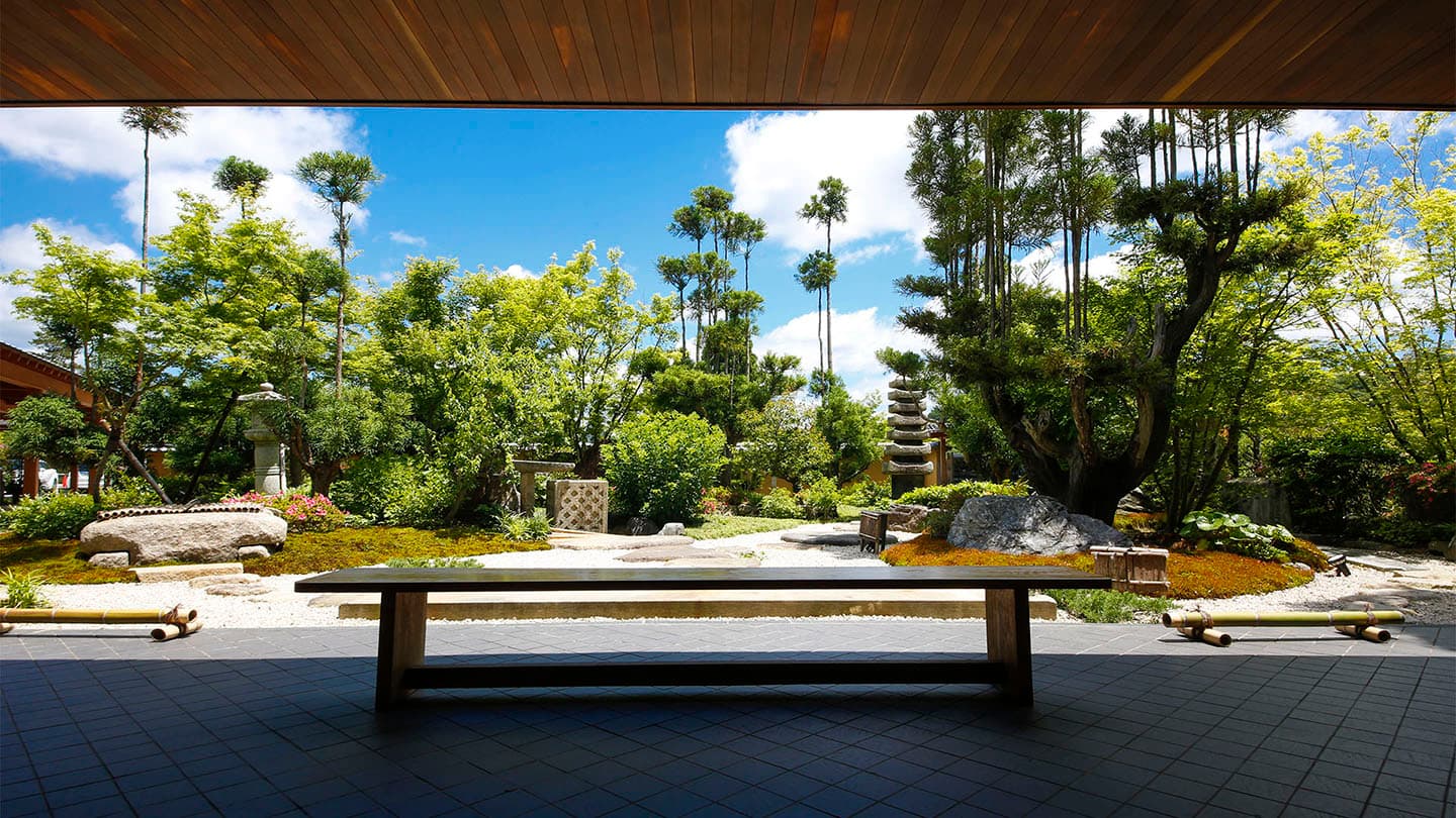 Manicured Japanese strolling garden with pruned pines and stone lanterns viewed from the lobby lounge bench at Ginsuiso Choraku