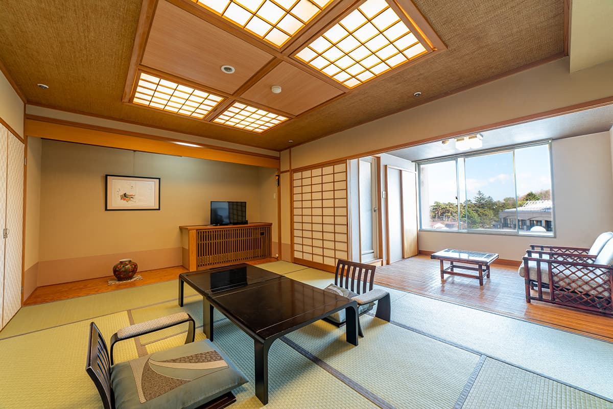Spacious tatami guest room with low table, shoji screens and a town-view window