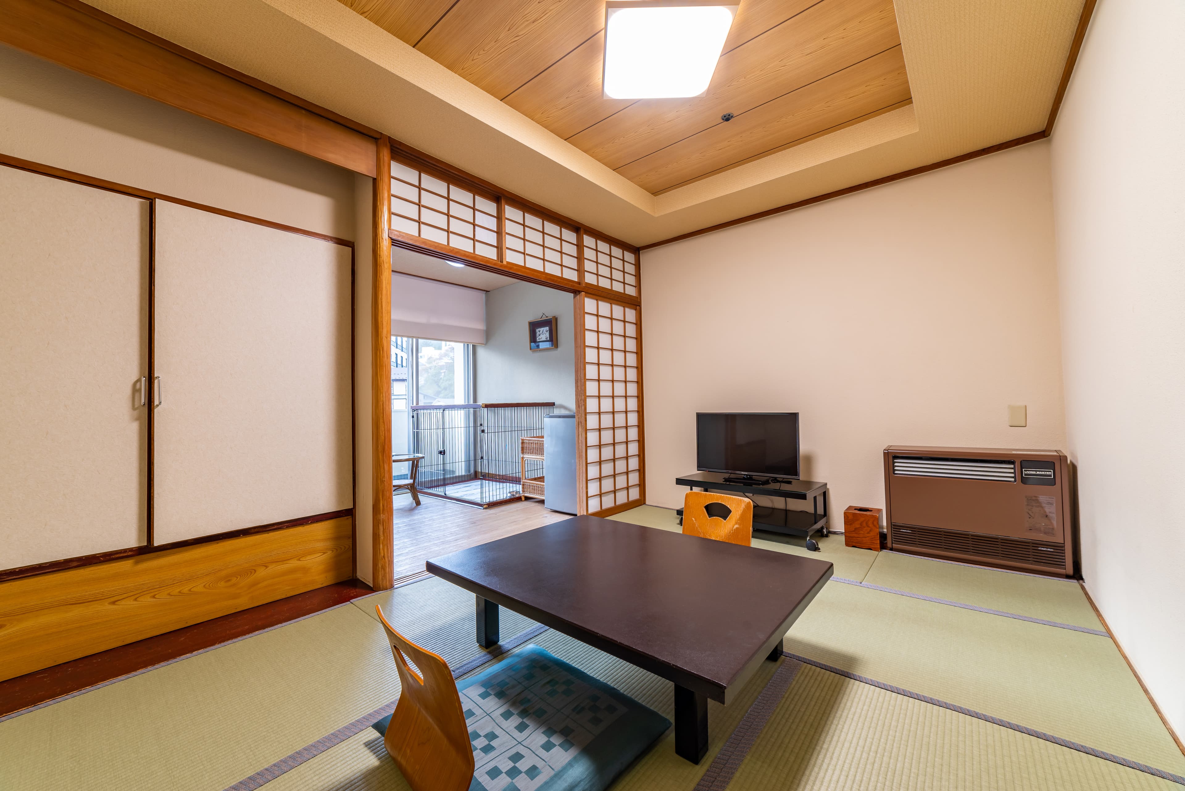 Cozy compact tatami room with a low table and balcony beyond shoji partitions