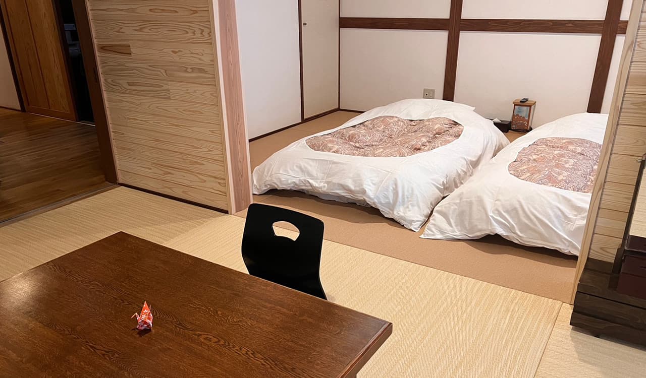 Tatami guest room at Tokiwaso with two futon beds laid out and a low wooden table, Dogo Onsen