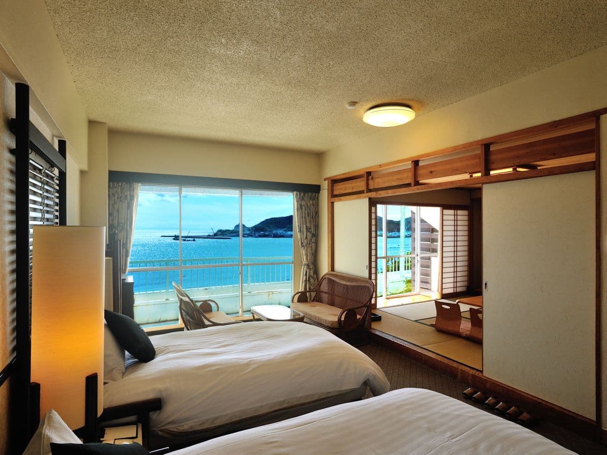 Sea-view guest room with twin beds and adjoining tatami space overlooking the Ibusuki coastline