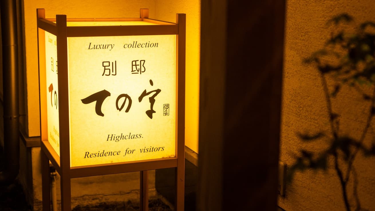Illuminated paper andon lantern signage at the inn entrance glowing at night