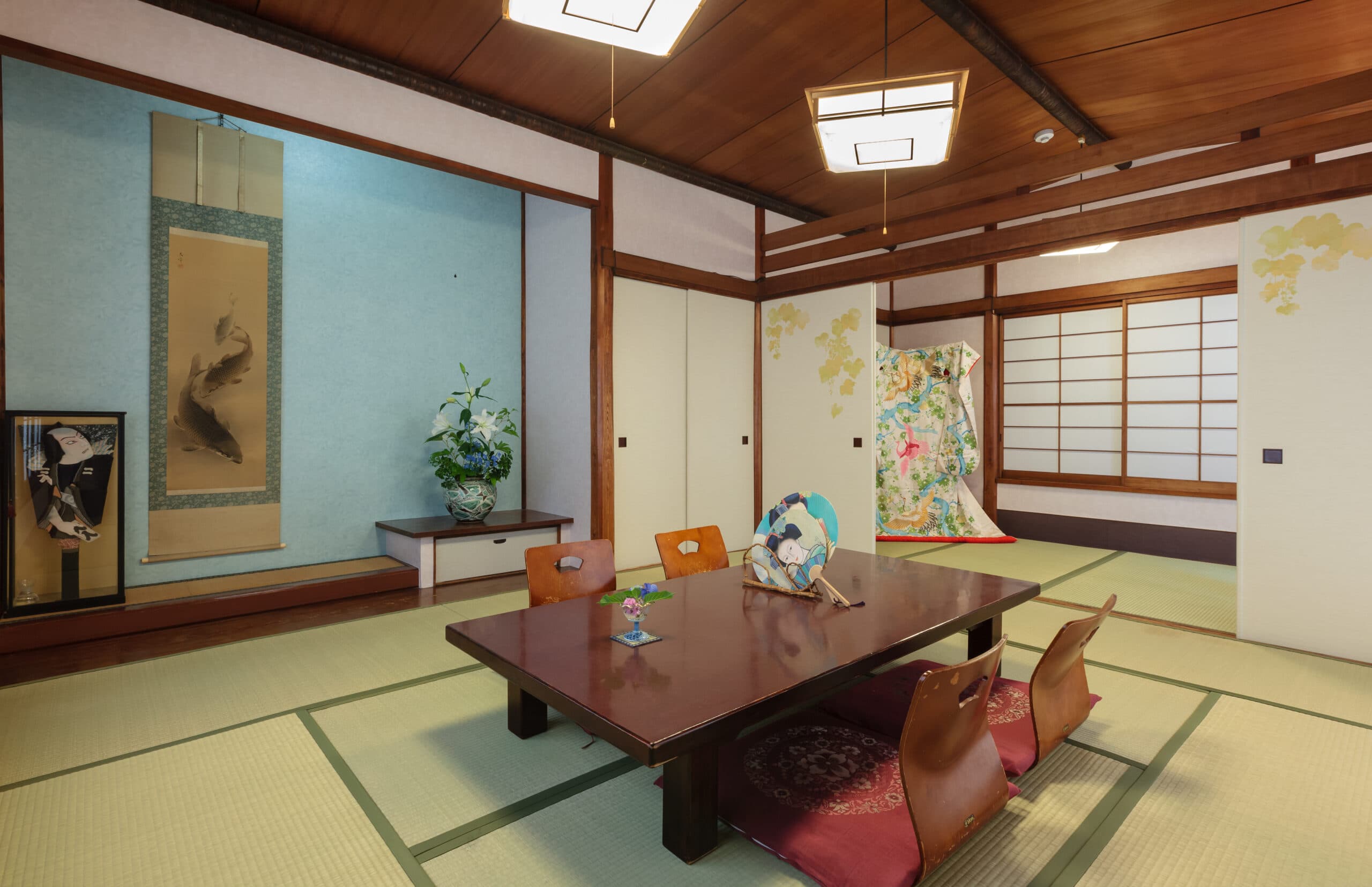 Spacious tatami guest room at Ito Ryokan Tokyo with hanging scroll, tokonoma alcove and kimono display