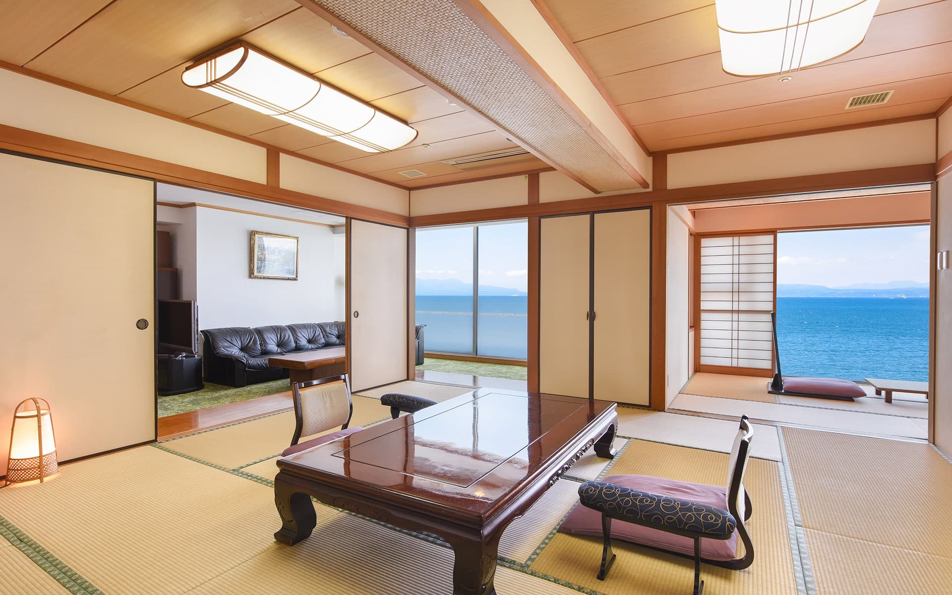 Spacious tatami guest room at Ibusuki Kaijo Hotel with low lacquer table and floor-to-ceiling windows overlooking the sea